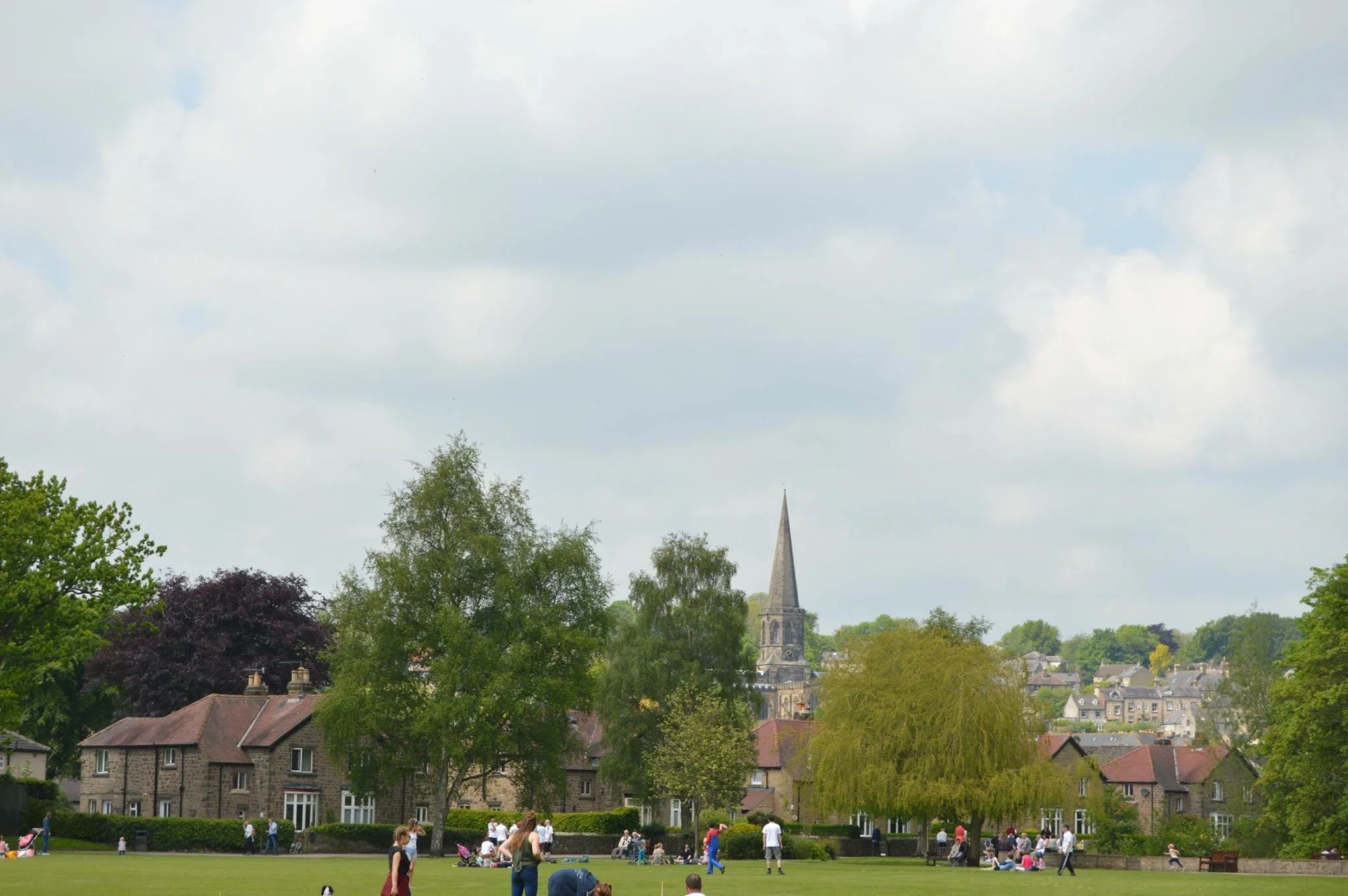 Lots of people enjoying the park with All Saint Church in the background. 