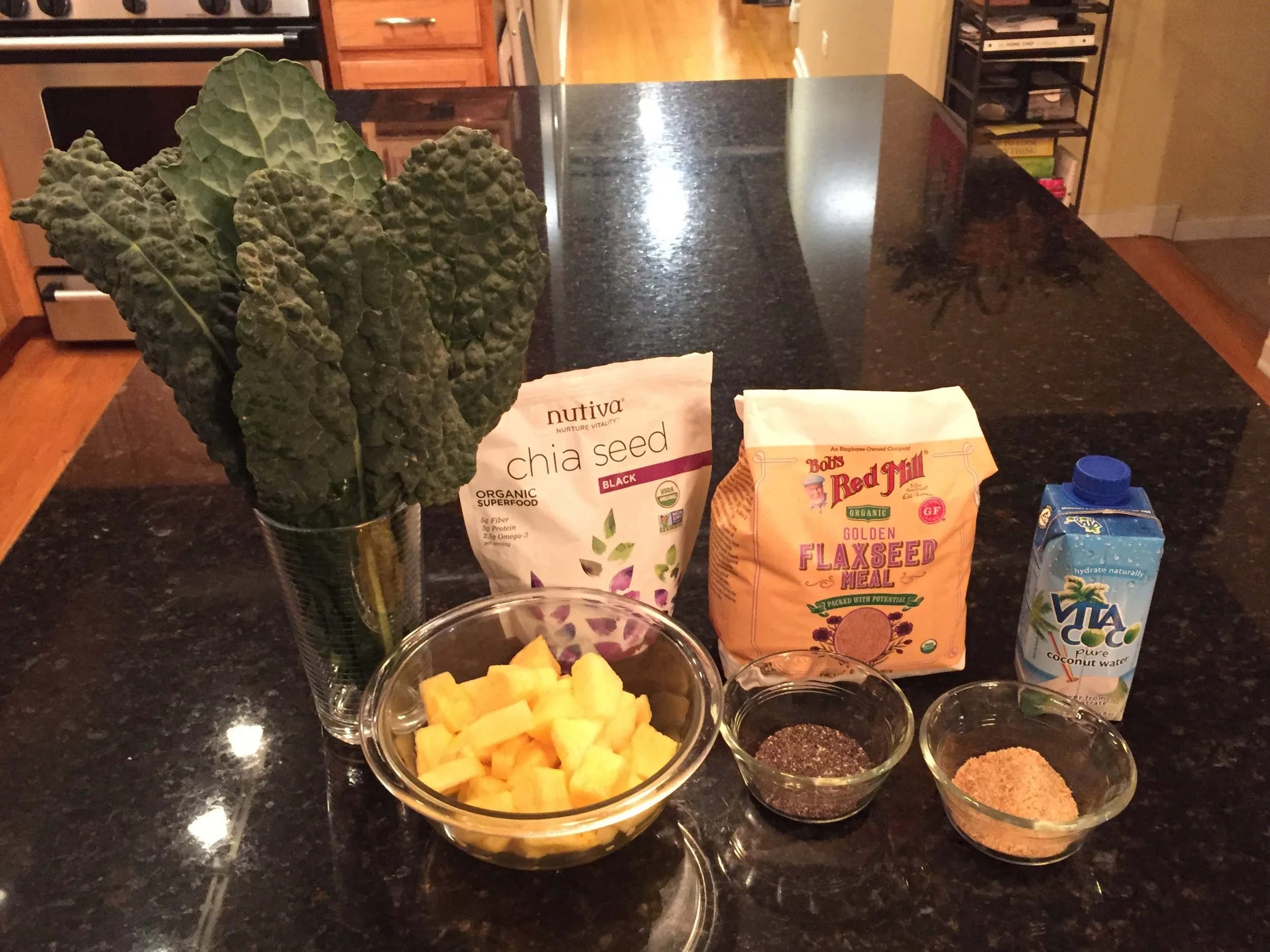 Pictured: Green chard, flax seed meal, coconut water, chopped mango & pineapple, I don't measure anymore. Basically I just fill the blender with fruit & coconut water first, then flax seed, followed by as much greens as I can fit in. Next I cover it all with more regular water. Our finished drink is more like a juice than a smoothie. Chia seeds go into each individual serving last.