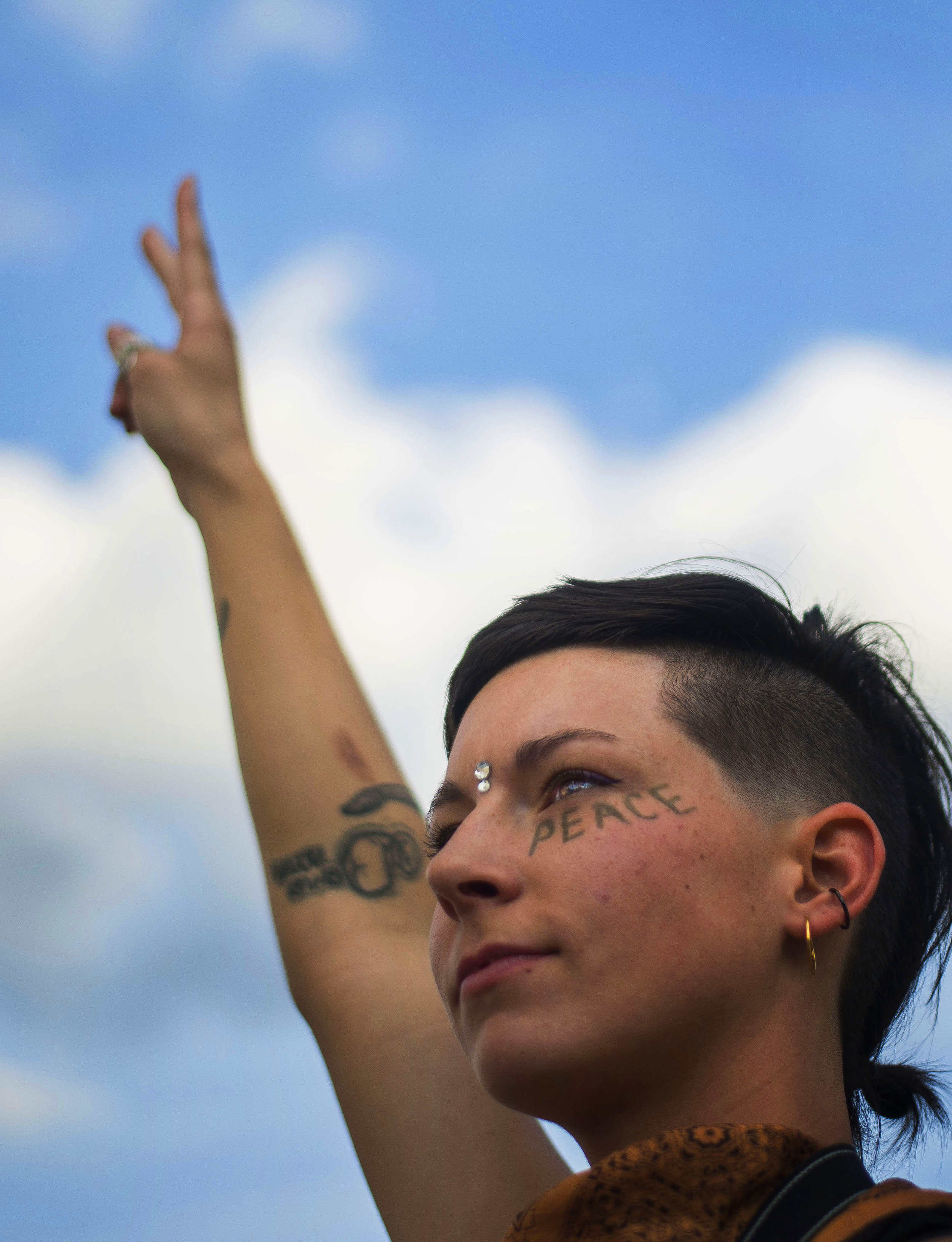 Audrey Conn, 25, stands with a peace sign in the air on the corner of Clinton and Berry streets on June 10, 2016, during the Silent Protest. Many passerbys took photos and videos; those driving honked their horns. 