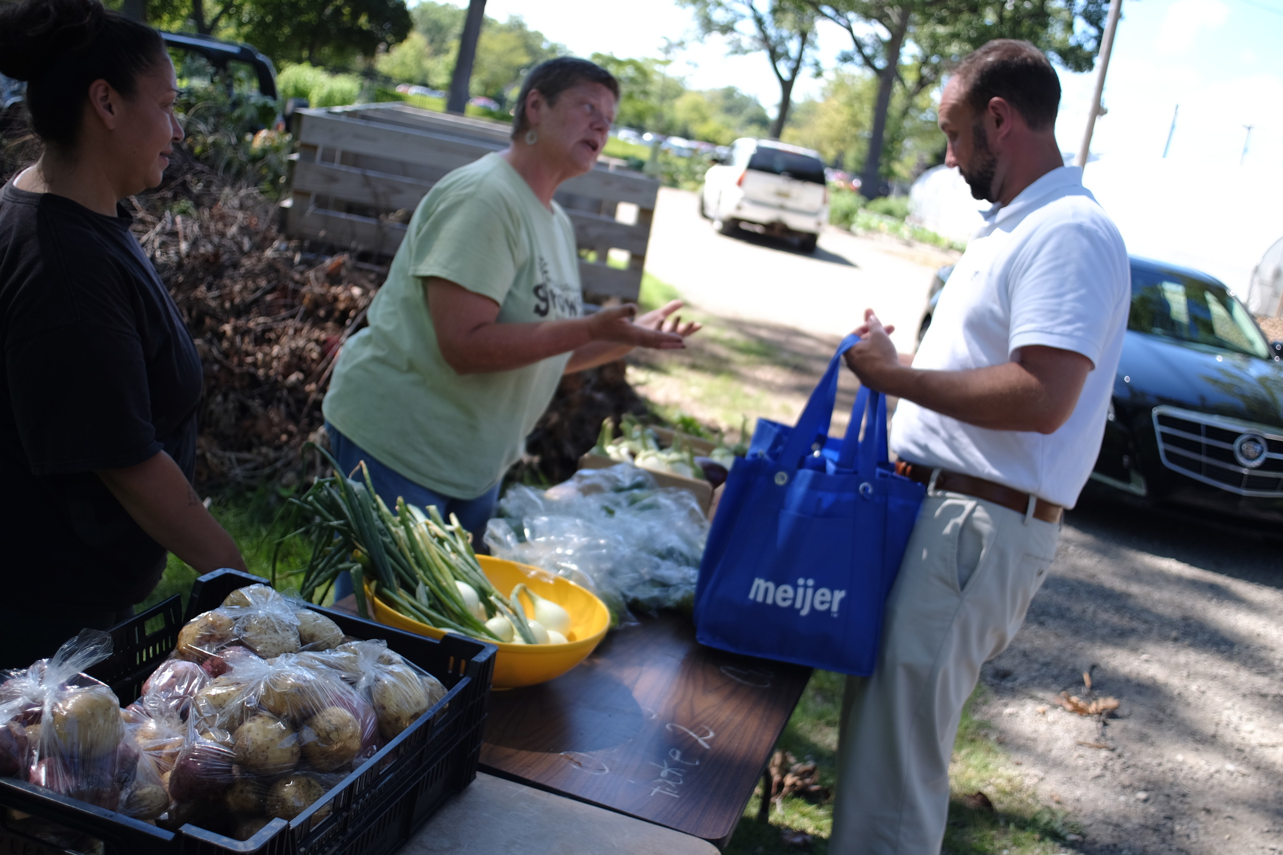 Laurie Wieschowski the farm manager, helps a CSA participant choose their weekly organic veggies at the Mercy Hospital Hackley Campus farm site.