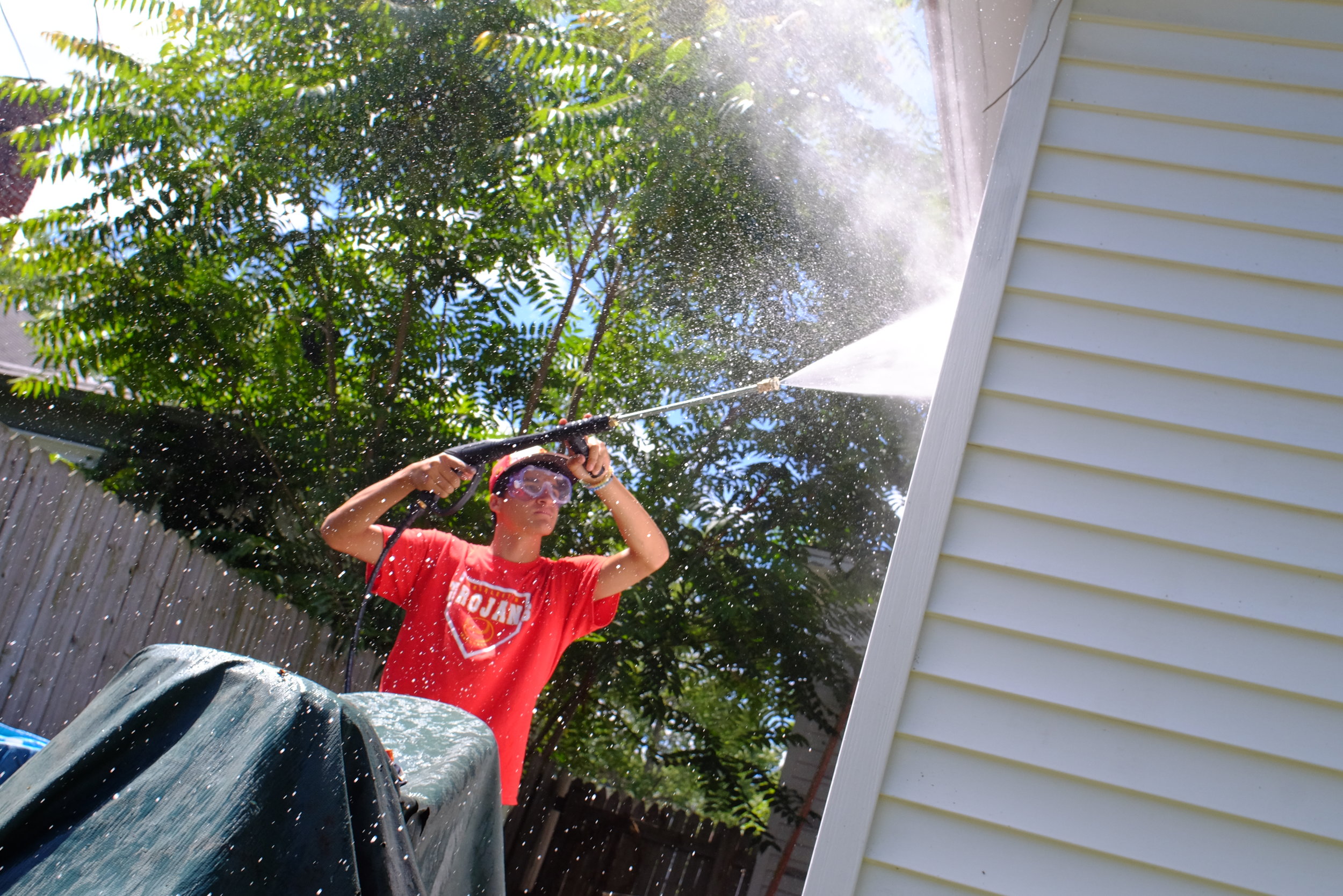 Volunteer from Catholic Heart work Camp cleaning siding on 4th street.