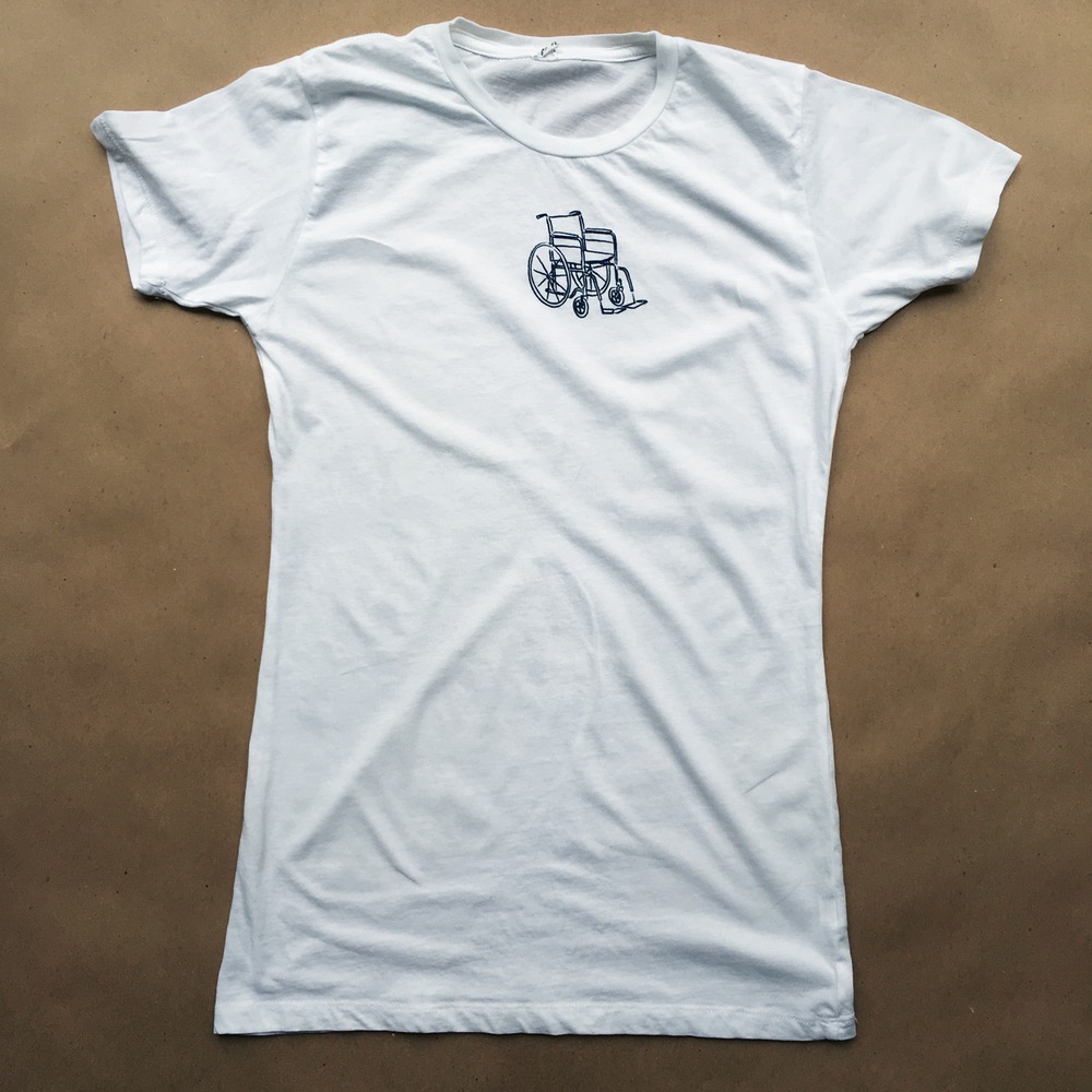 Pictured: White t-shirt with black wheelchair illustration in the center of the top half of the shirt. 