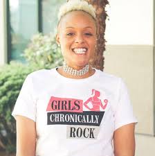 Keisha Greaves smiles at the camera, wearing a “Girls Chronically Rock” shirt.