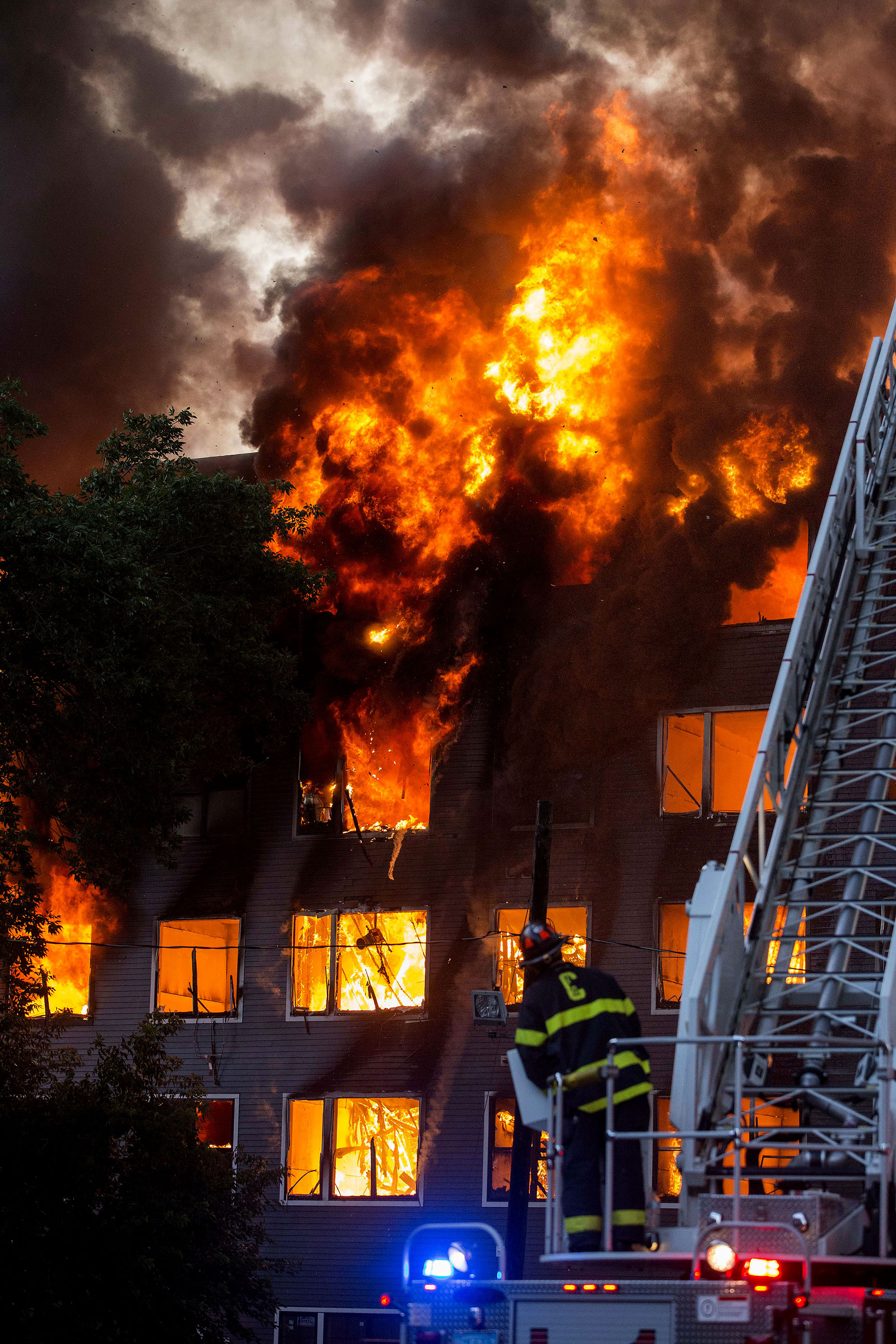  A Cambridge firefighter watches as fire and smoke pours from a fully involved building at an 8-alarm fire where multiple buildings were fully involved in Waltham on Sunday, July 23, 2017. (Scott Eisen for The Boston Globe) 