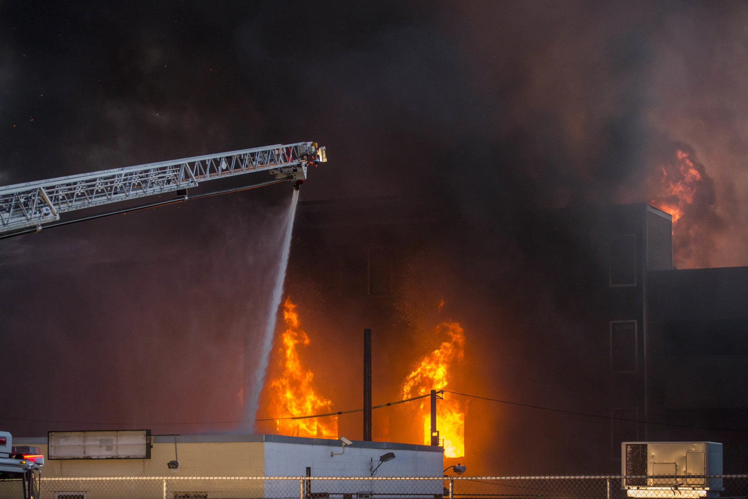 Fire pours from a building at an 8 alarm fire in Waltham on Sunday, July 23, 2017 that involved multiple structures. (Scott Eisen for The Boston Globe)