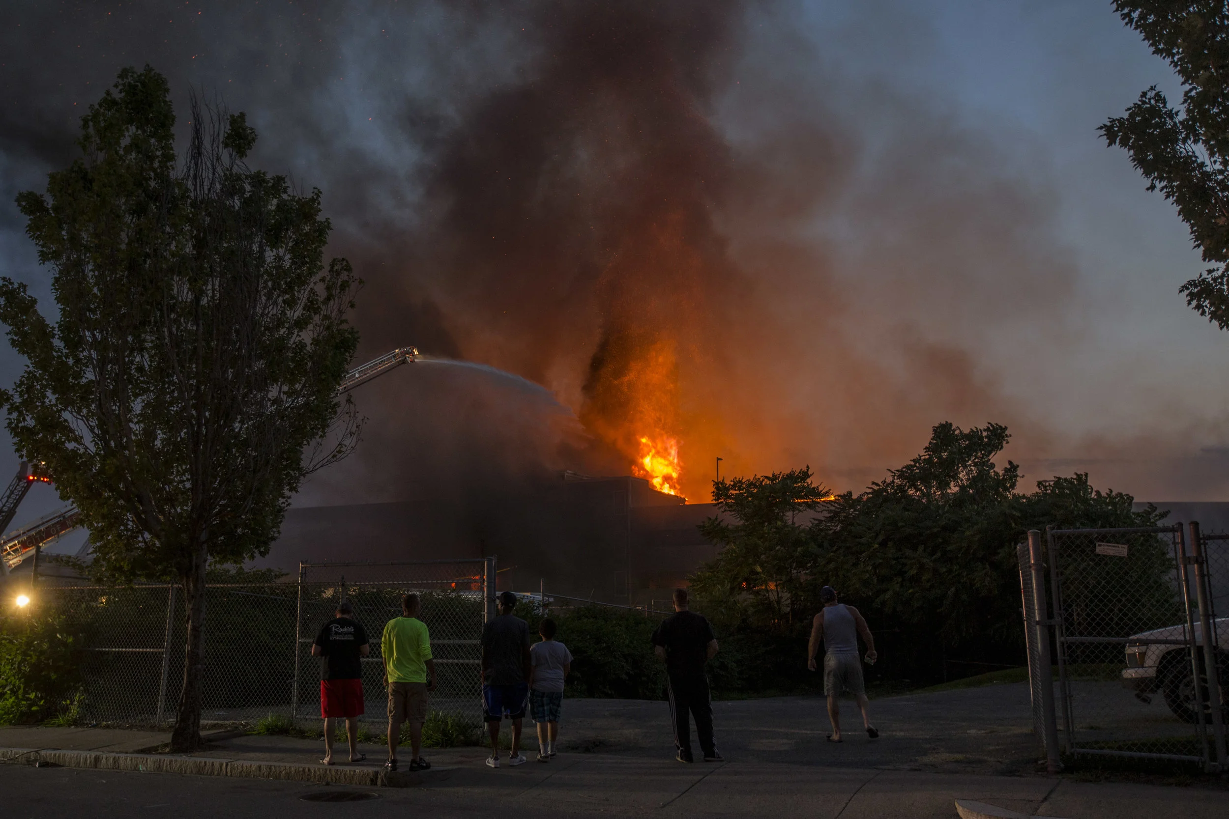 Onlookers watch an 8 alarm fire in Waltham on Sunday, July 23, 2017 that involved multiple structures. (Scott Eisen for The Boston Globe)