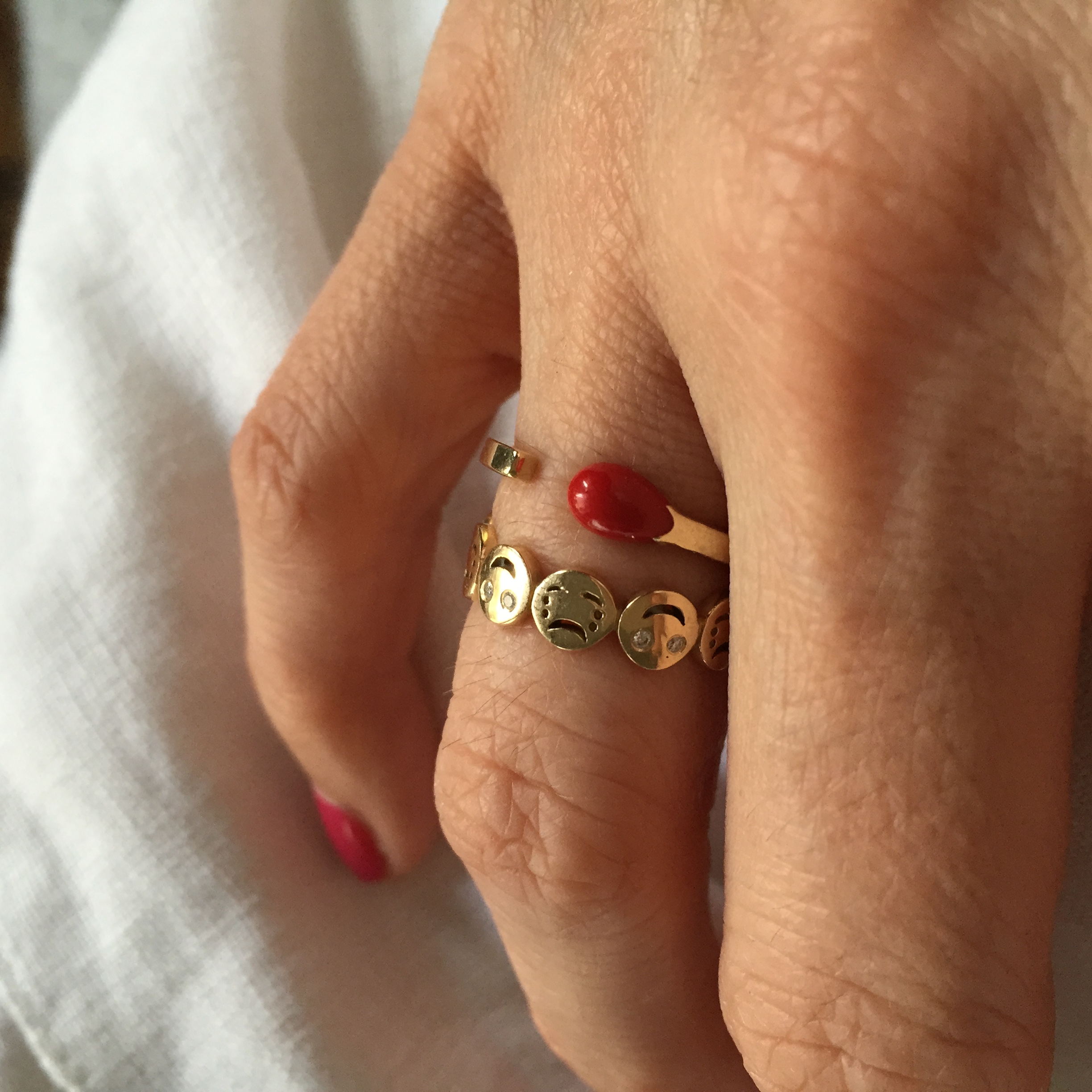 Nadine wearing her  Alison Lou "Happy or Sad?" ring  with a  Nora Kogan Red Matchstick  ring, both available at Stone &amp; Strand. 