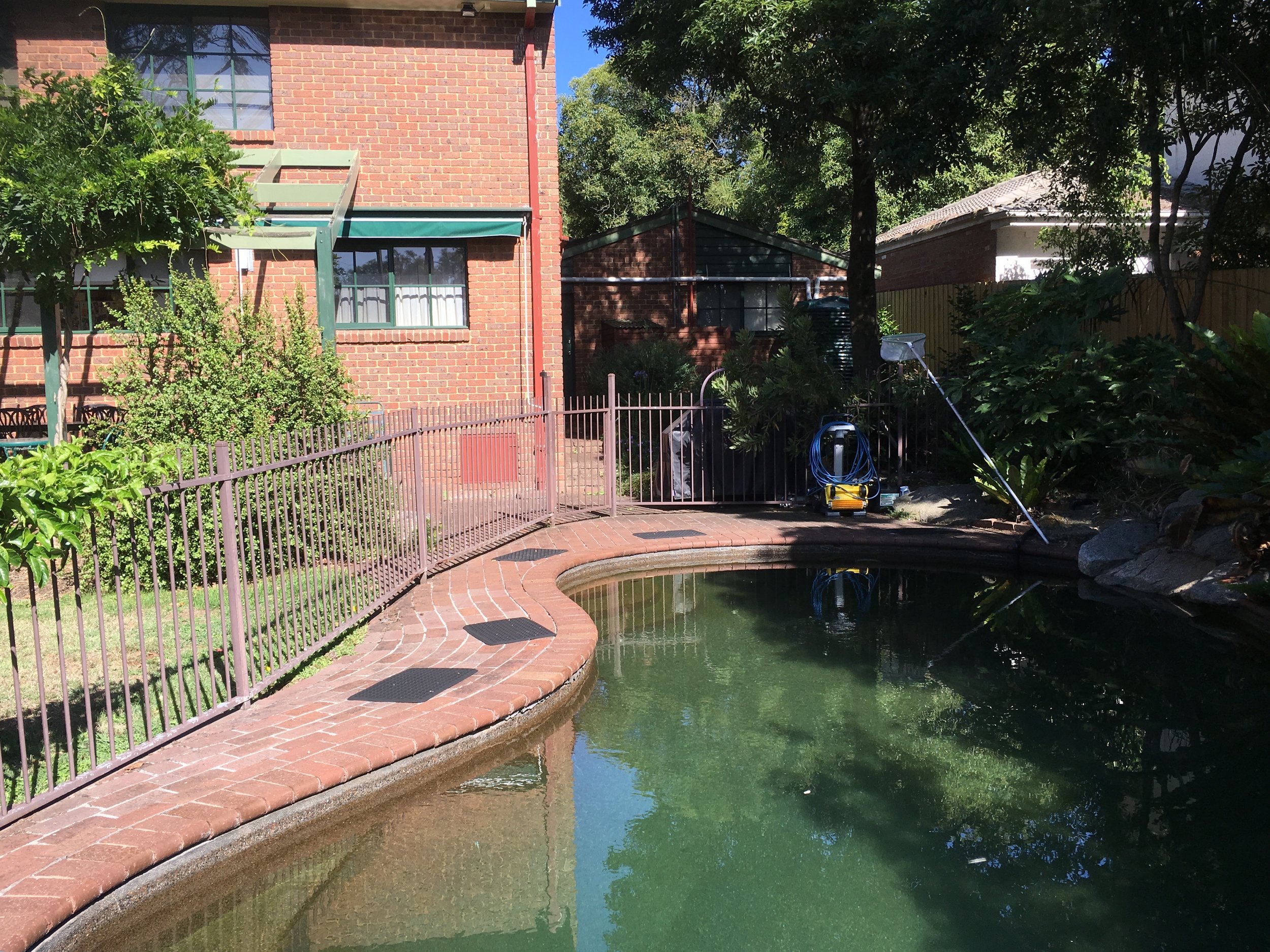BEFORE: Small entertaining area attached to the house, and not much visibility into the pool area. The pool is sadly dated and not very appealing.