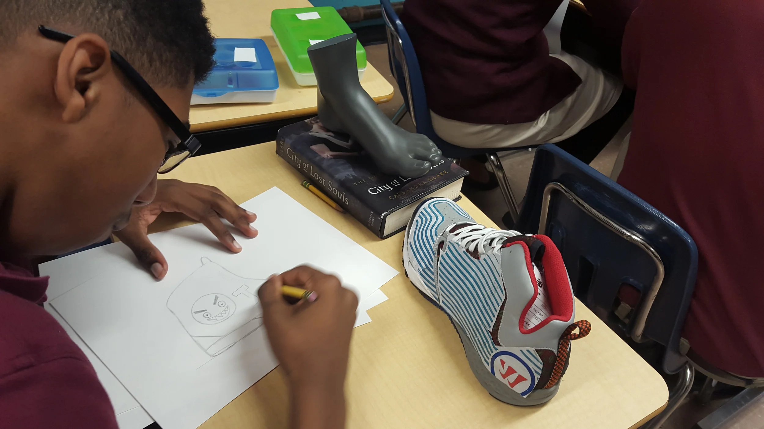 Guest artist Sa'rah Melinda, a designer for the Adidas custom men's line, visited Boston Prep art classes to teach students about the application of art in the design profession. Here, Rodney Owens creates his own show design. 