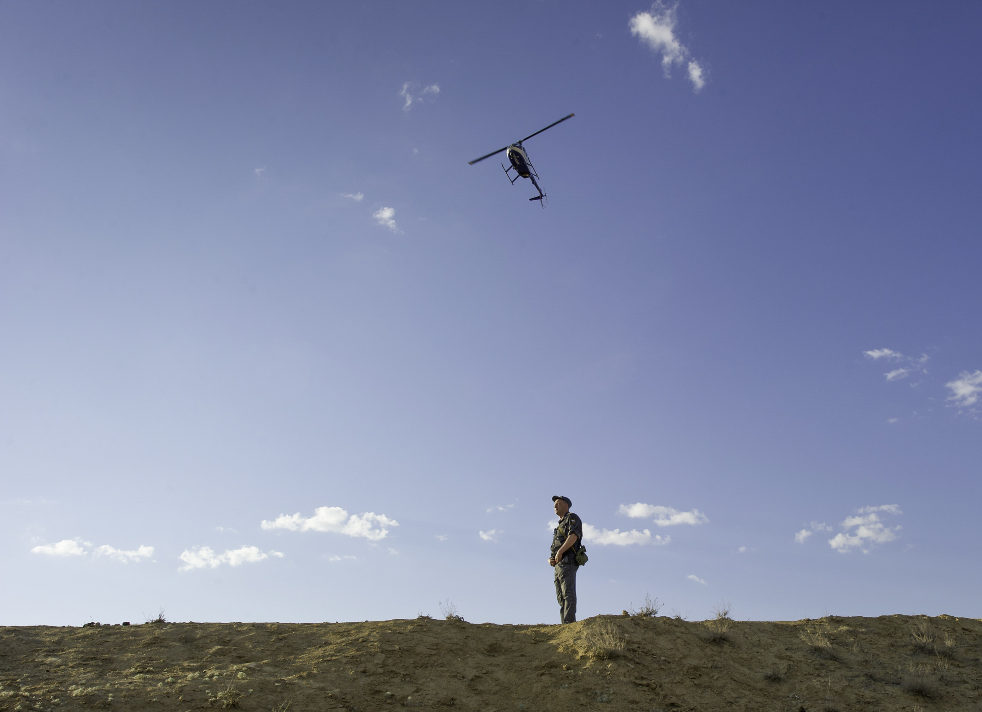  A Russian security guard stands watch as a Russian military helicopter flies overhead during the rollout of the Soyuz TMA-02M rocket to the launch pad at the Baikonur Cosmodrome in Kazakhstan on Sunday, June 5, 2011. (NASA/Carla Cioffi) 