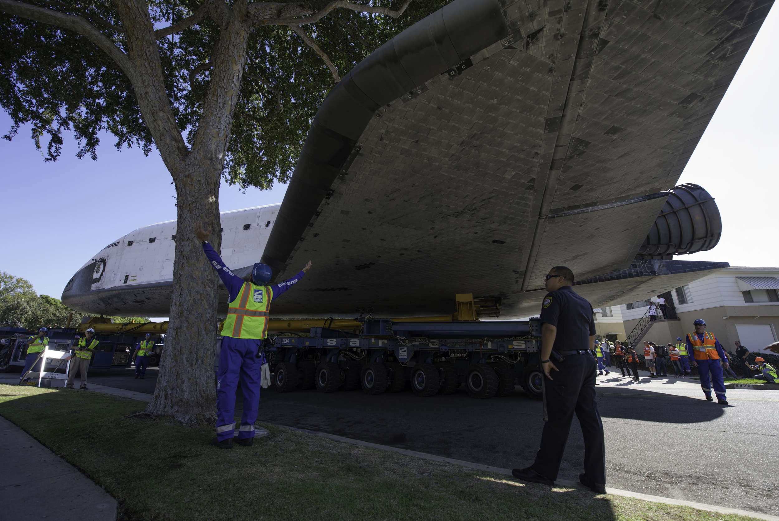 A technician for the Over Land Transporter (OLT) carrying the space shuttle Endeavour signals how much room is available between a tree and the orbiter’s wing, Saturday, Oct. 13, 2012, as it maneuvers its way through the streets of Inglewood, Calif.