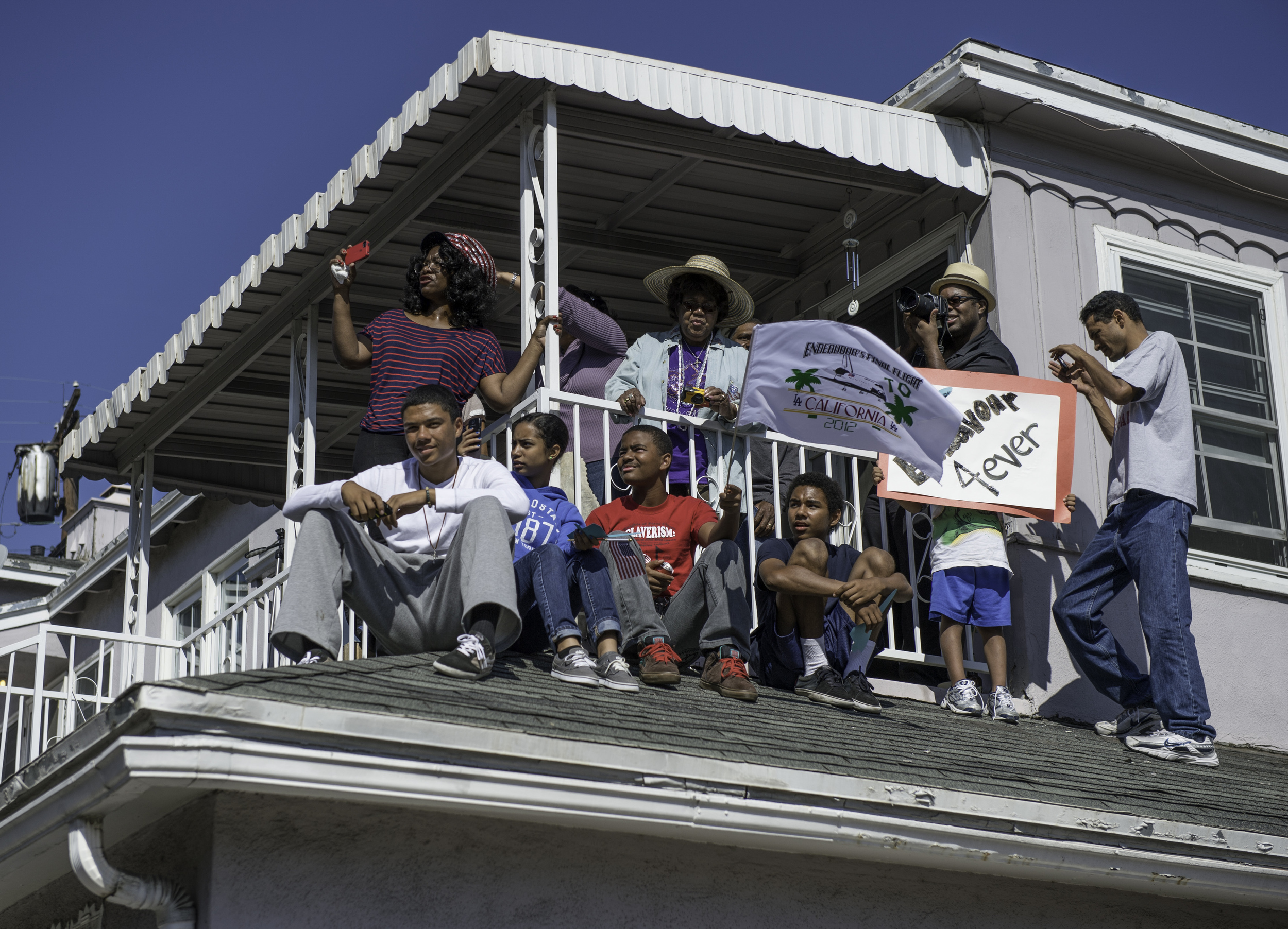  People gather as space shuttle Endeavour passes through their neighborhood in Inglewood, CA on Saturday, Oct. 13, 2012. Endeavour, built as a replacement for space shuttle Challenger, completed 25 missions, spent 299 days in orbit, and orbited Earth