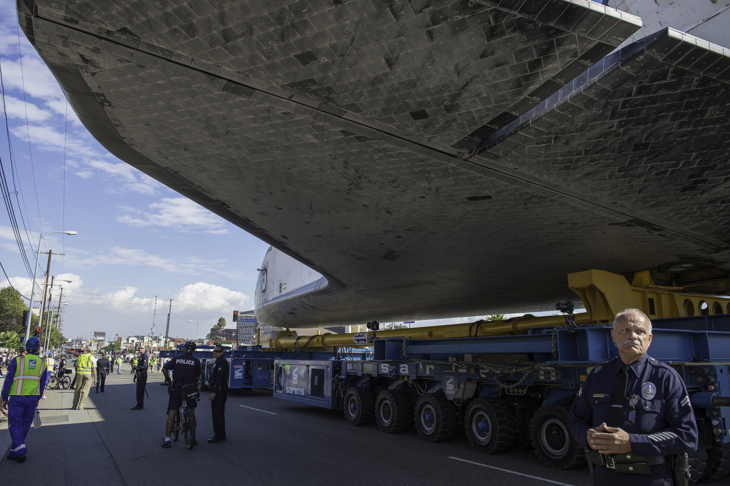 A policeman stands guard as space shuttle Endeavour passes by on its way to its new home at the California Science Center in Los Angeles, Friday, Oct. 12, 2012. Endeavour, built as a replacement for space shuttle Challenger, completed 25 missions, s