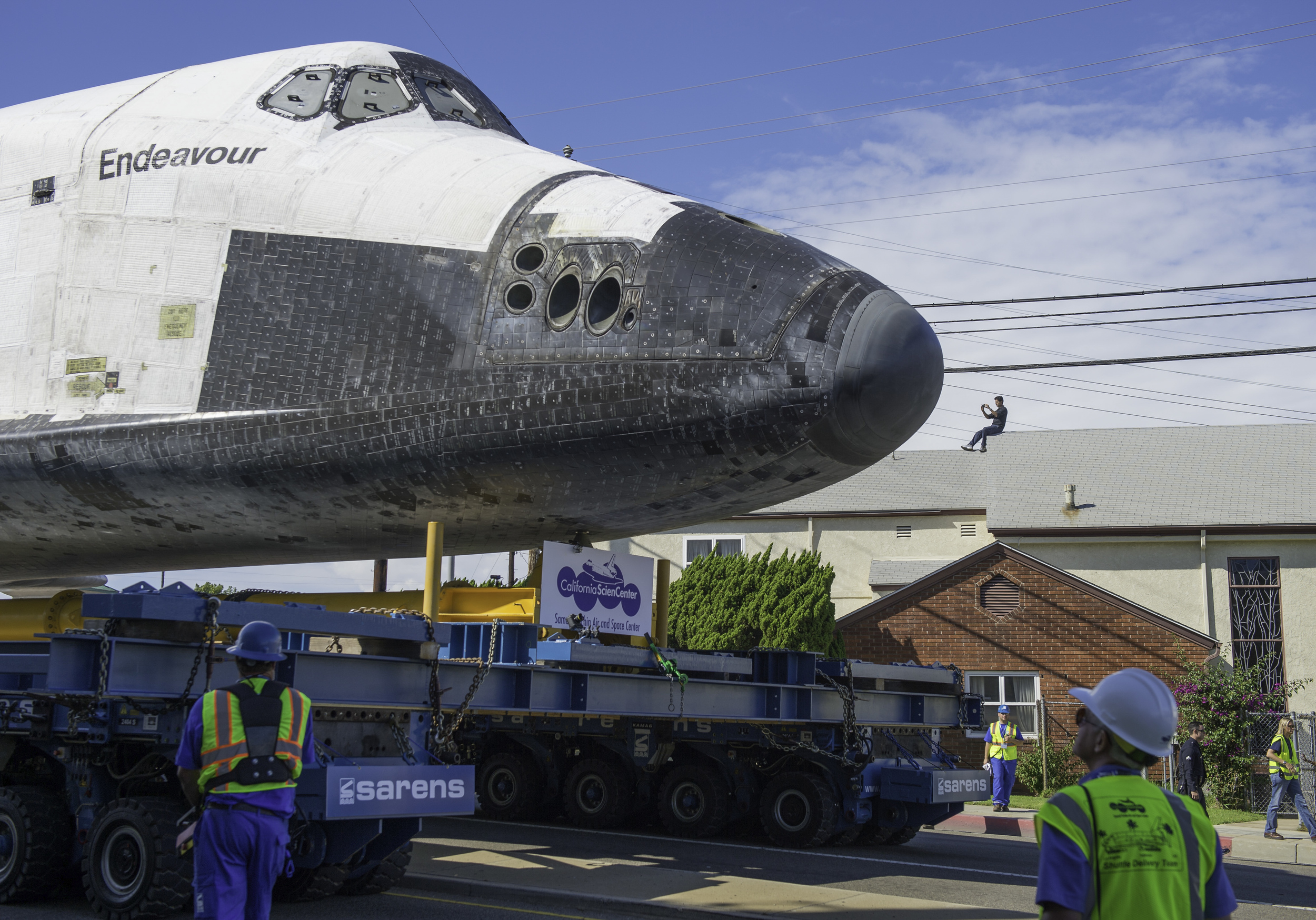 A spectator on the roof of a building photographs space shuttle Endeavour as it passes by on its way to its new home at the California Science Center in Los Angeles, Friday, Oct. 12, 2012. Endeavour, built as a replacement for space shuttle Challeng