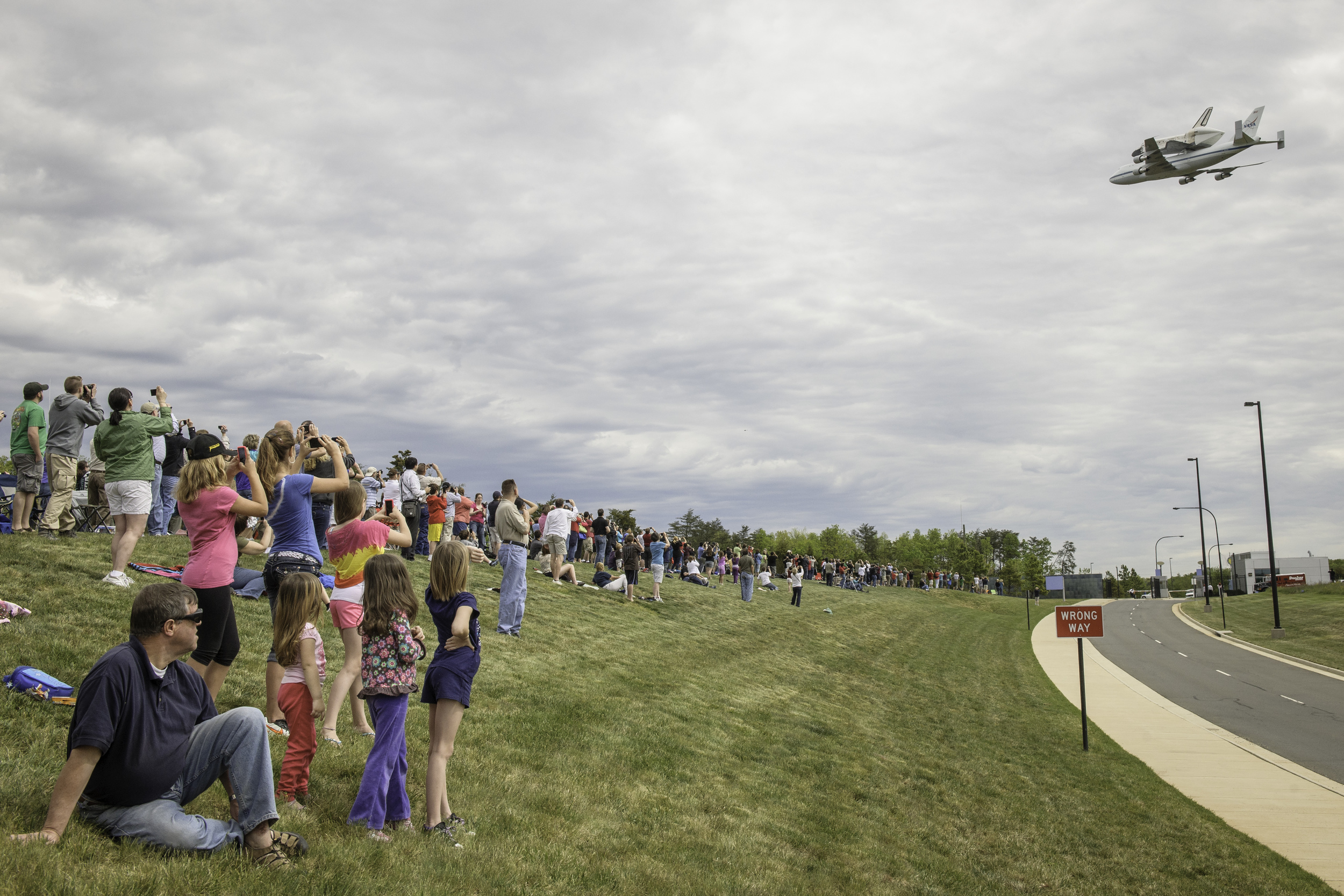 Spectators watch as space shuttle Discovery, mounted atop a NASA 747 Shuttle Carrier Aircraft (SCA) flies over the National Air and Space Museum’s Steven F. Udvar-Hazy Center, Tuesday, April 17, 2012, in Chantilly, Va. Discovery, the first orbiter r