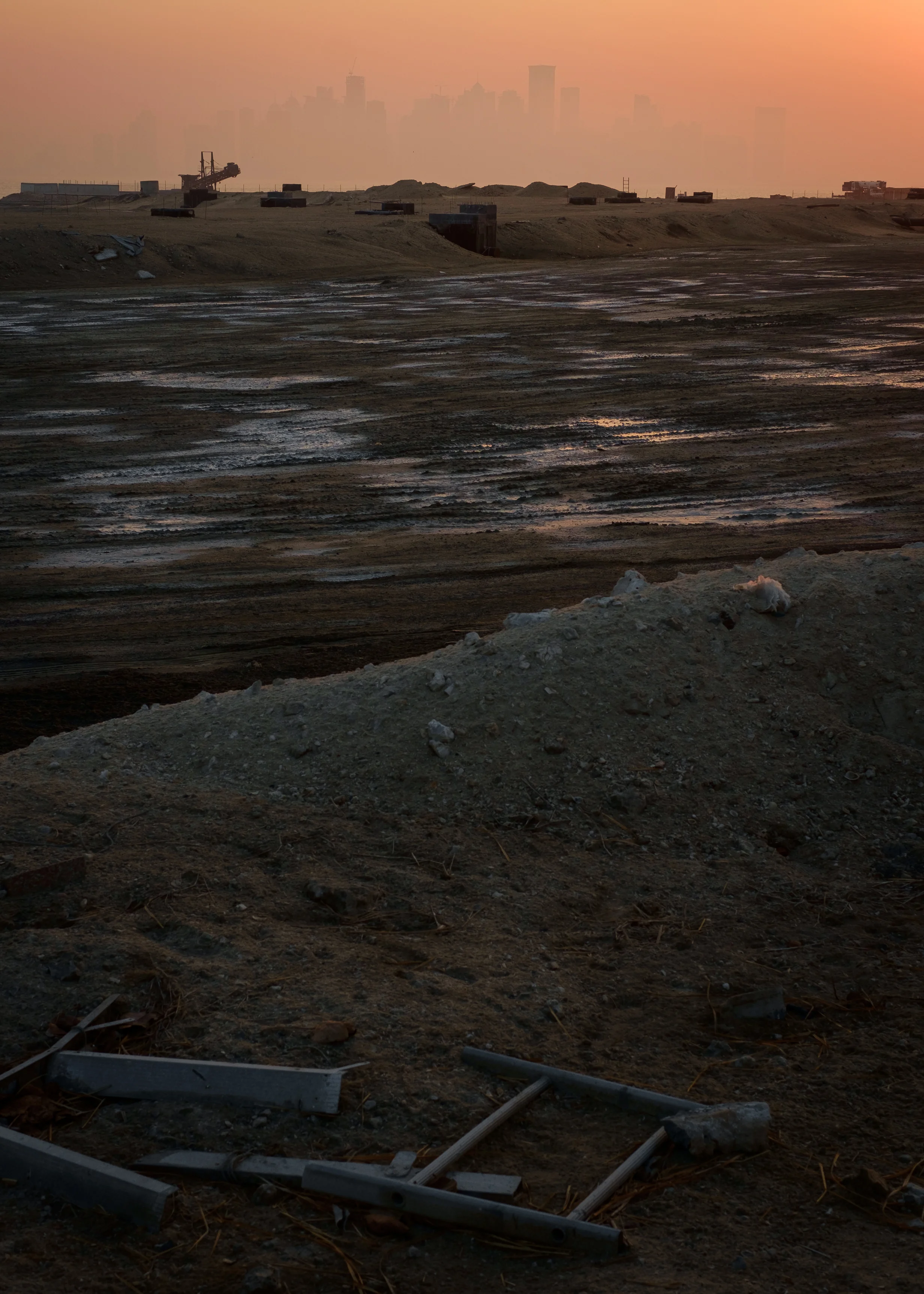 Looking out across the water from a construction site on The Pearl, the skyline of Doha’s West Bay neighborhood is barely seen through the haze at sunset.