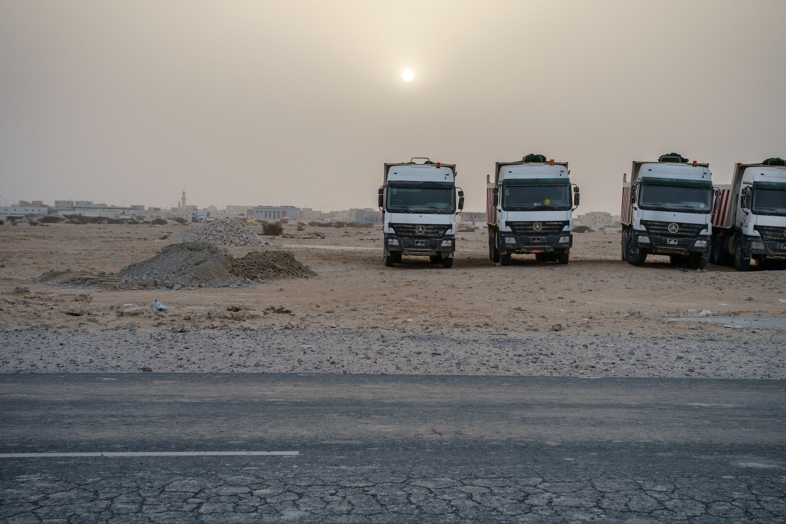  Dumpster trucks are lined up on their day off as the sun sets behind them. Desert dust is often in the air creating an other-worldly atmosphere. 