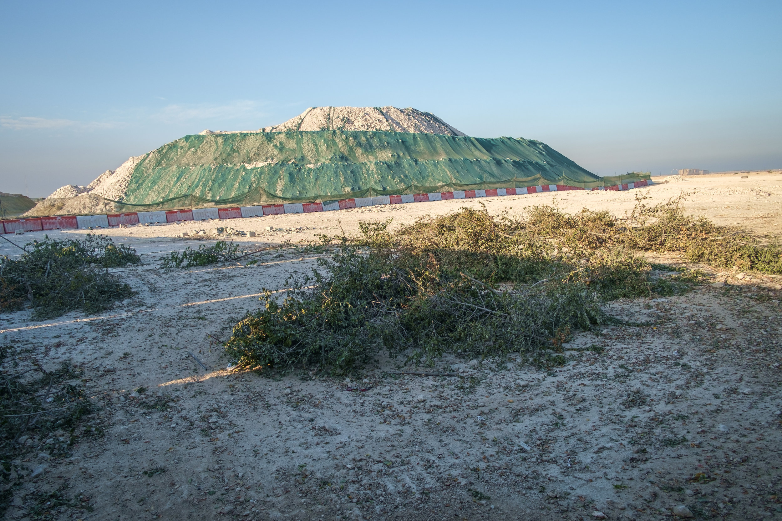  A massive mound of dirt and rock, echoing a half-built pyramid, is seen at a construction site just north of Doha.  