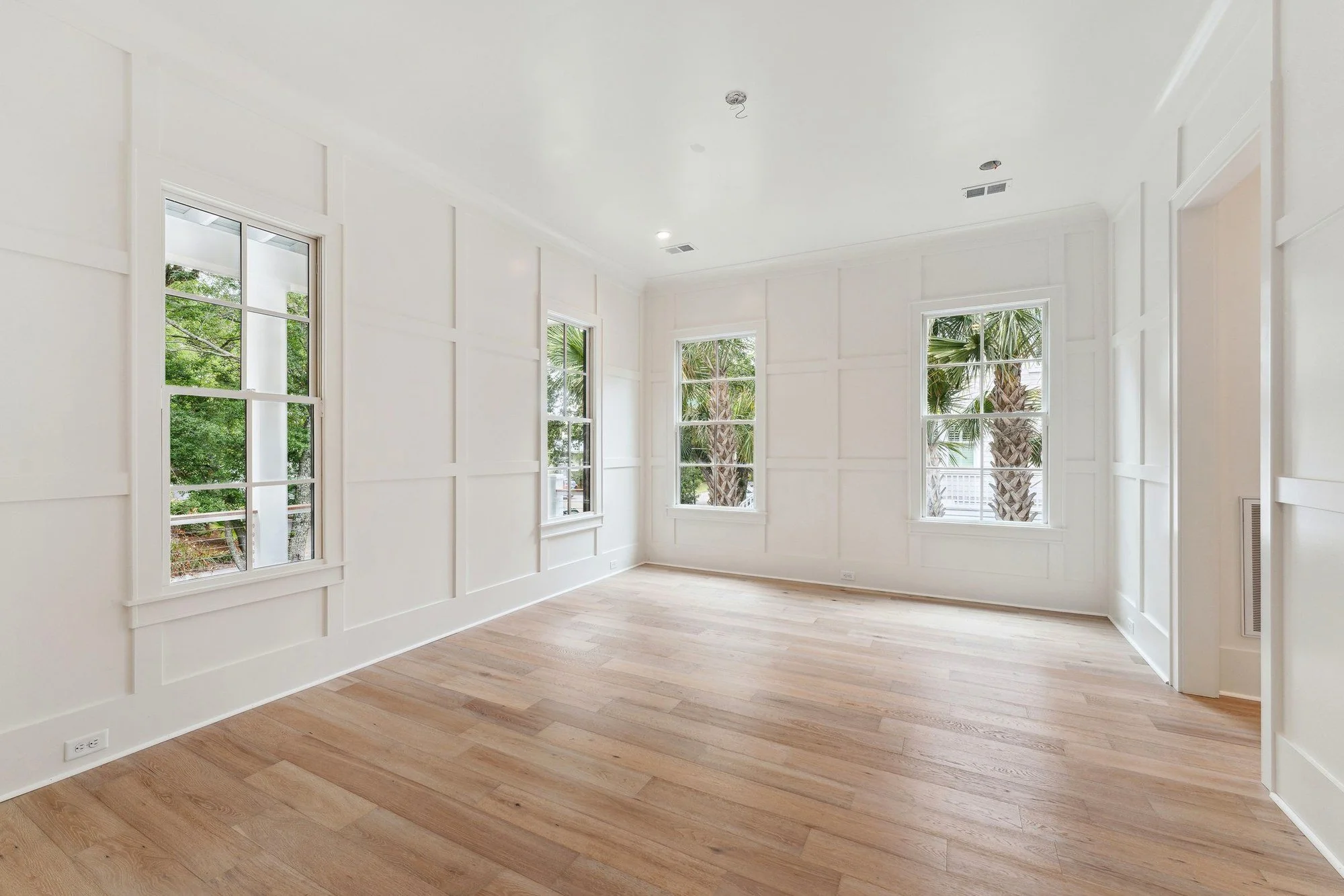 Paneled sitting room with a wall of windows into the oaks.