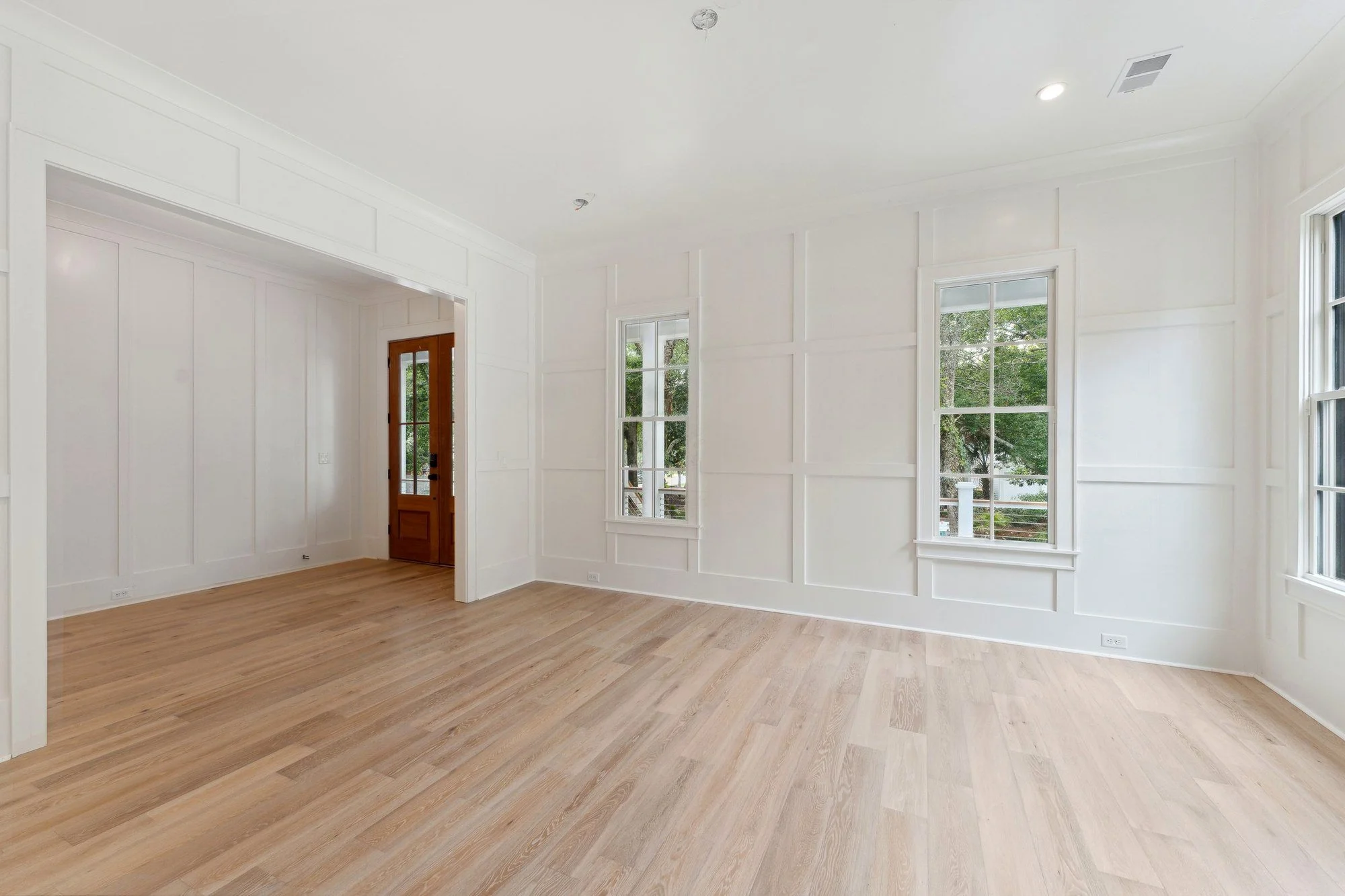 Formal room wrapped in board-and-batten paneling over white oak floors.