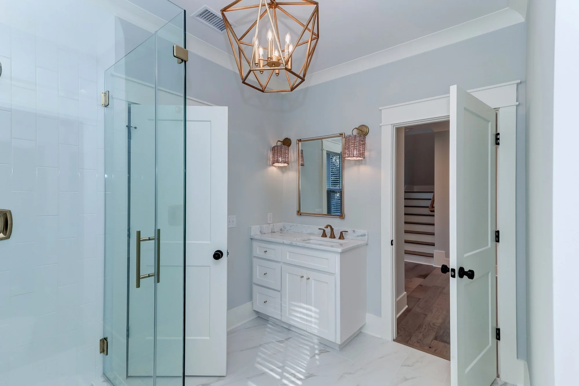 Guest bath with brass chandelier in a Mount Pleasant SC home by Iconic Developments