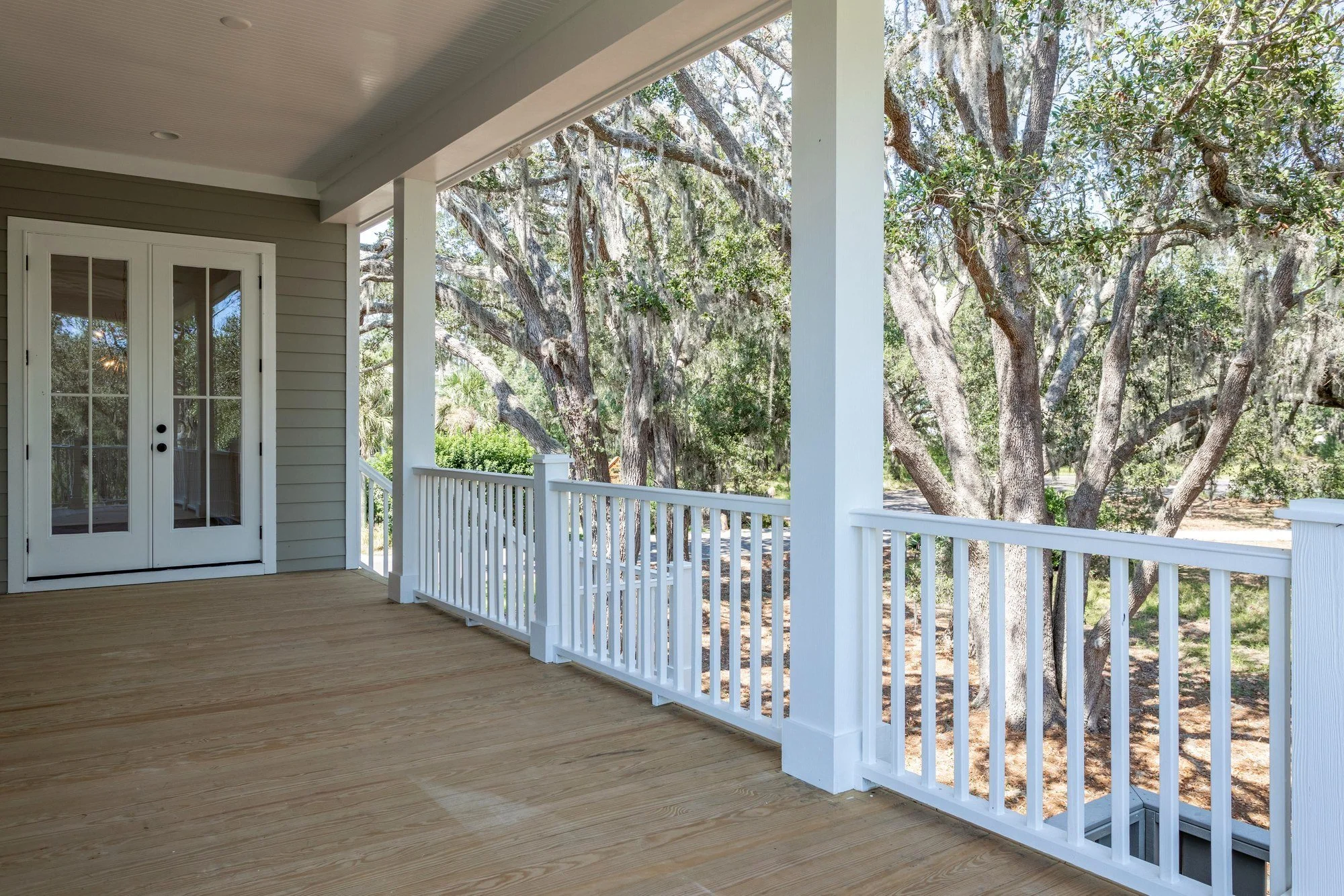 Wraparound porch overlooking live oaks at a Charleston SC home by Iconic Developments