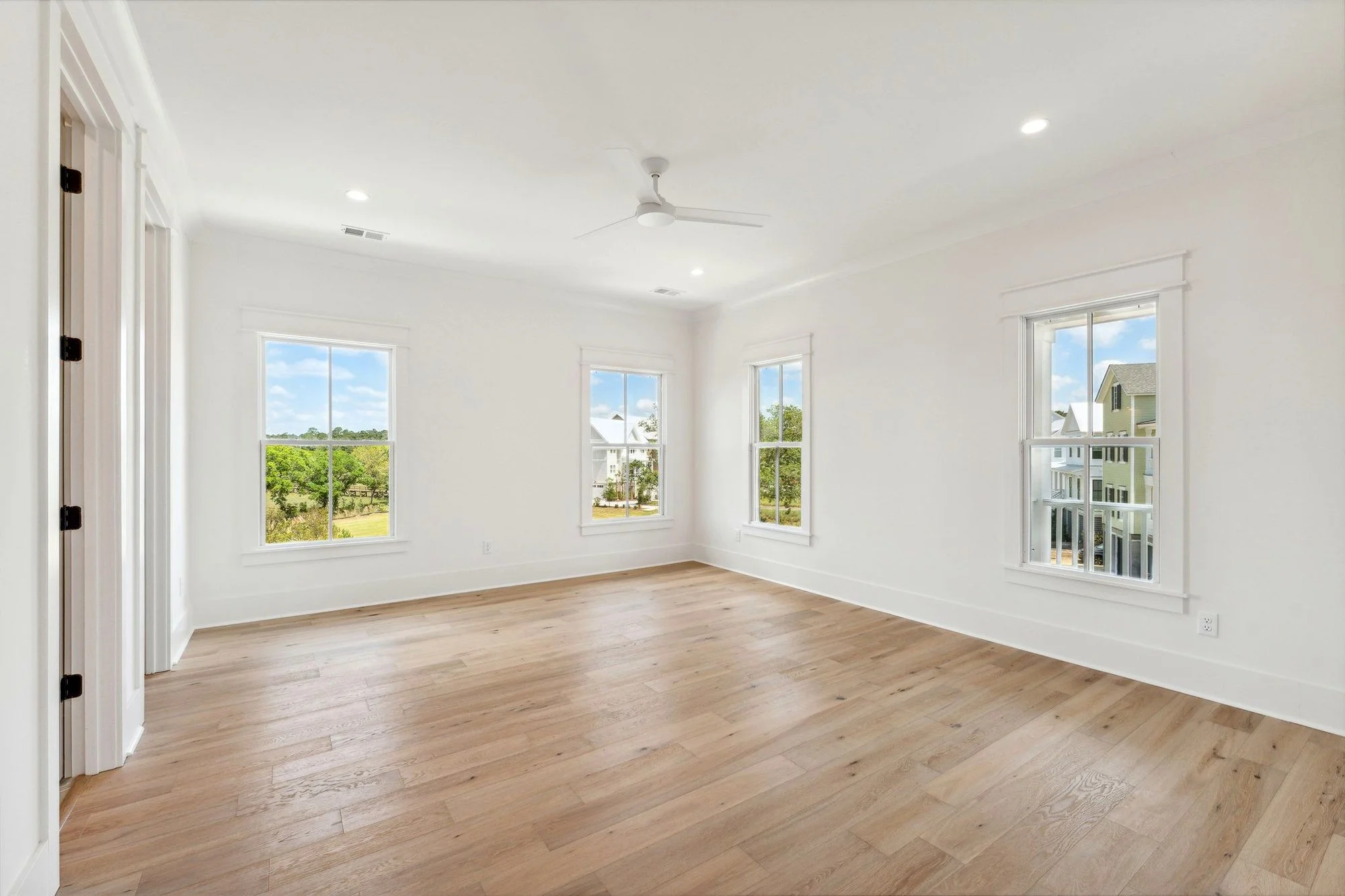 Bedroom with corner windows and white oak flooring in a Daniel Island SC custom home