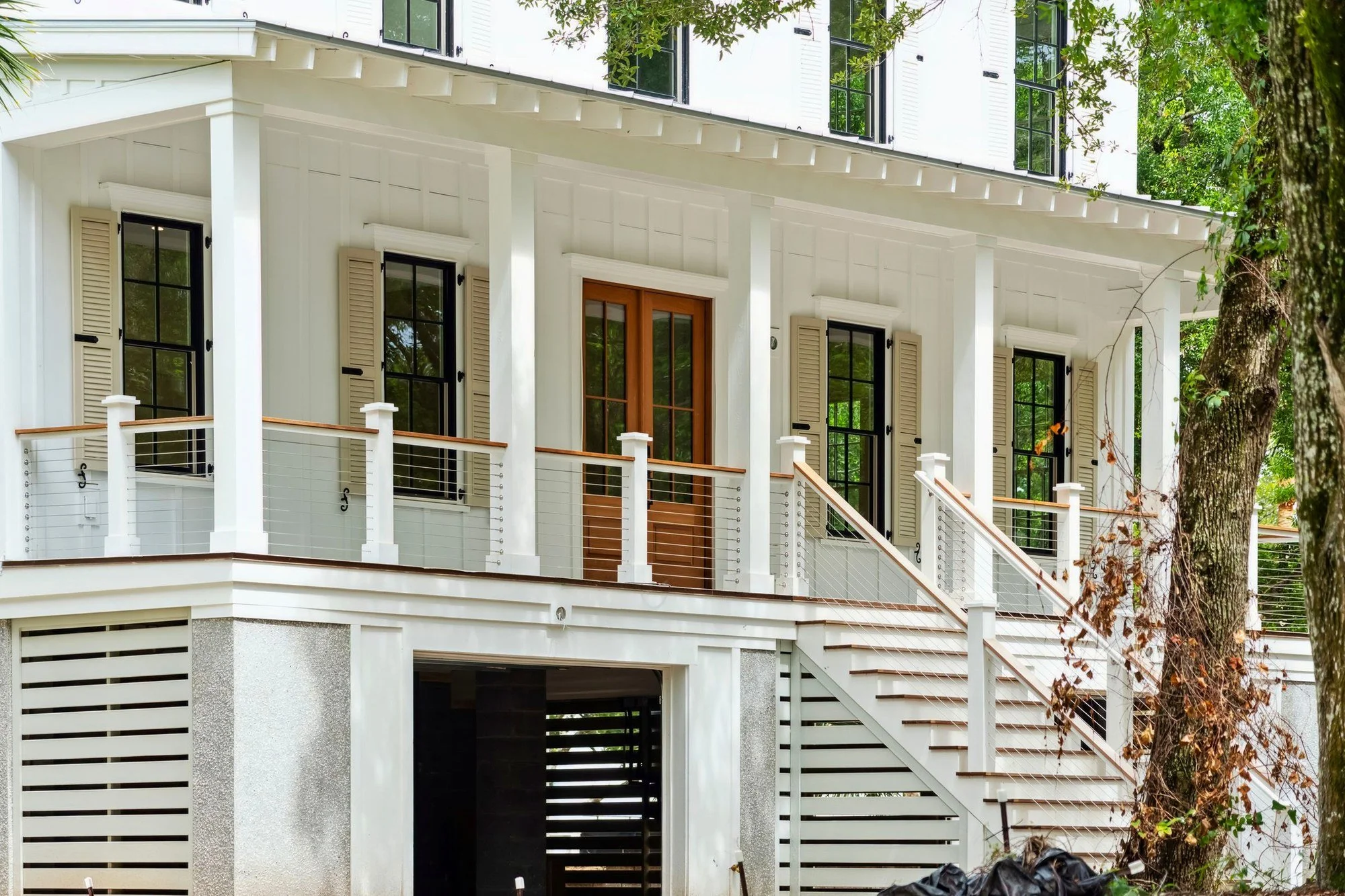 2 Driftwood Lane - front elevation of a raised custom home on Isle of Palms, with double porches and mahogany front doors.