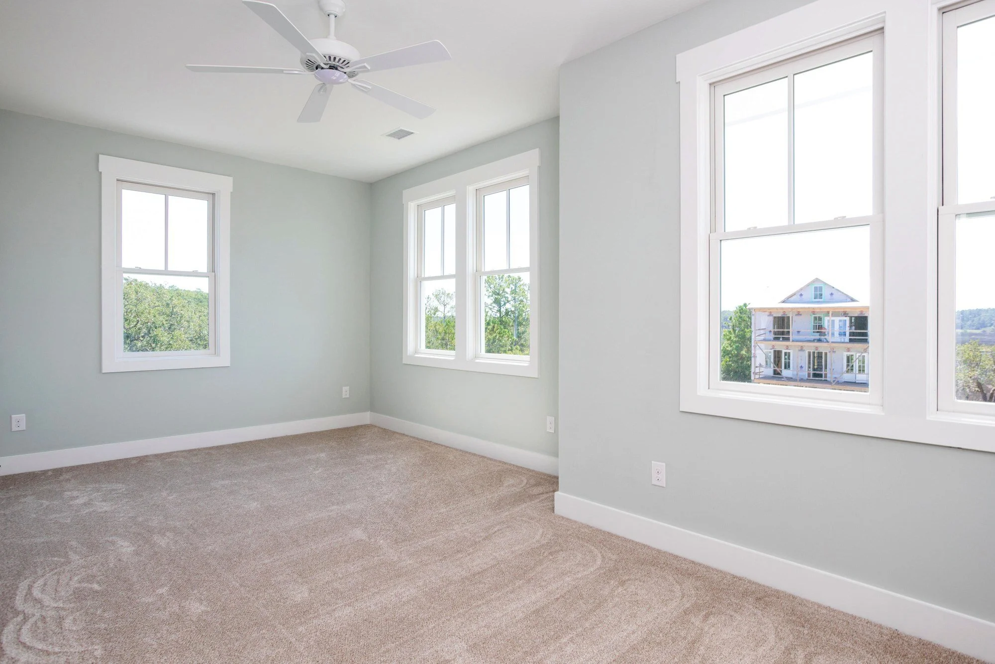 Bright guest bedroom with three windows in a Charleston SC luxury custom home build