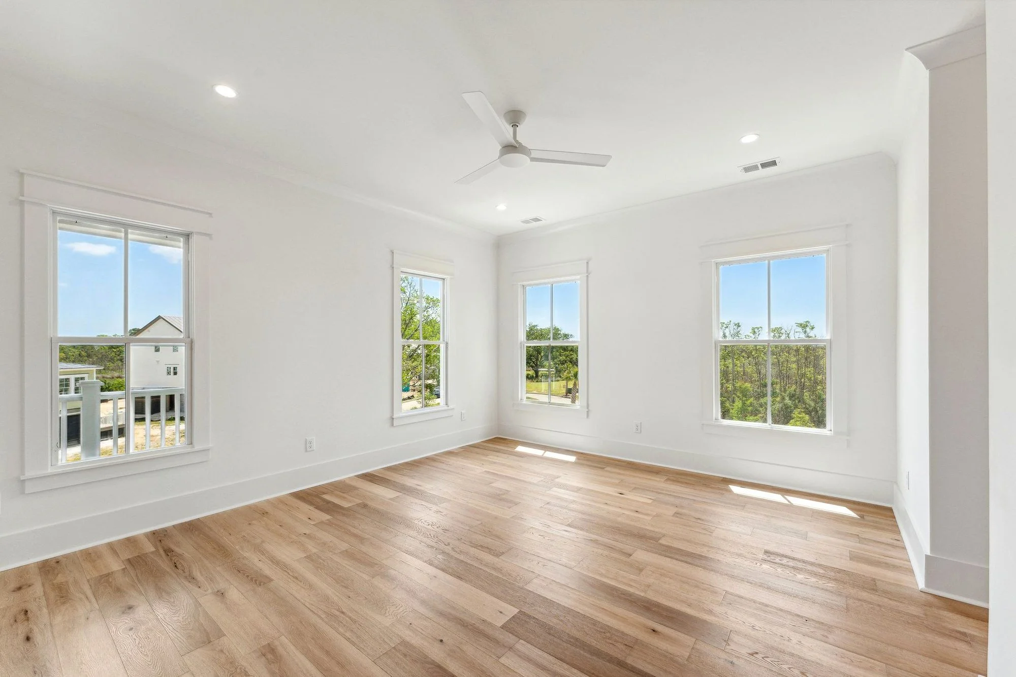 Light-filled bedroom with four windows in a Daniel Island SC home by Iconic Developments