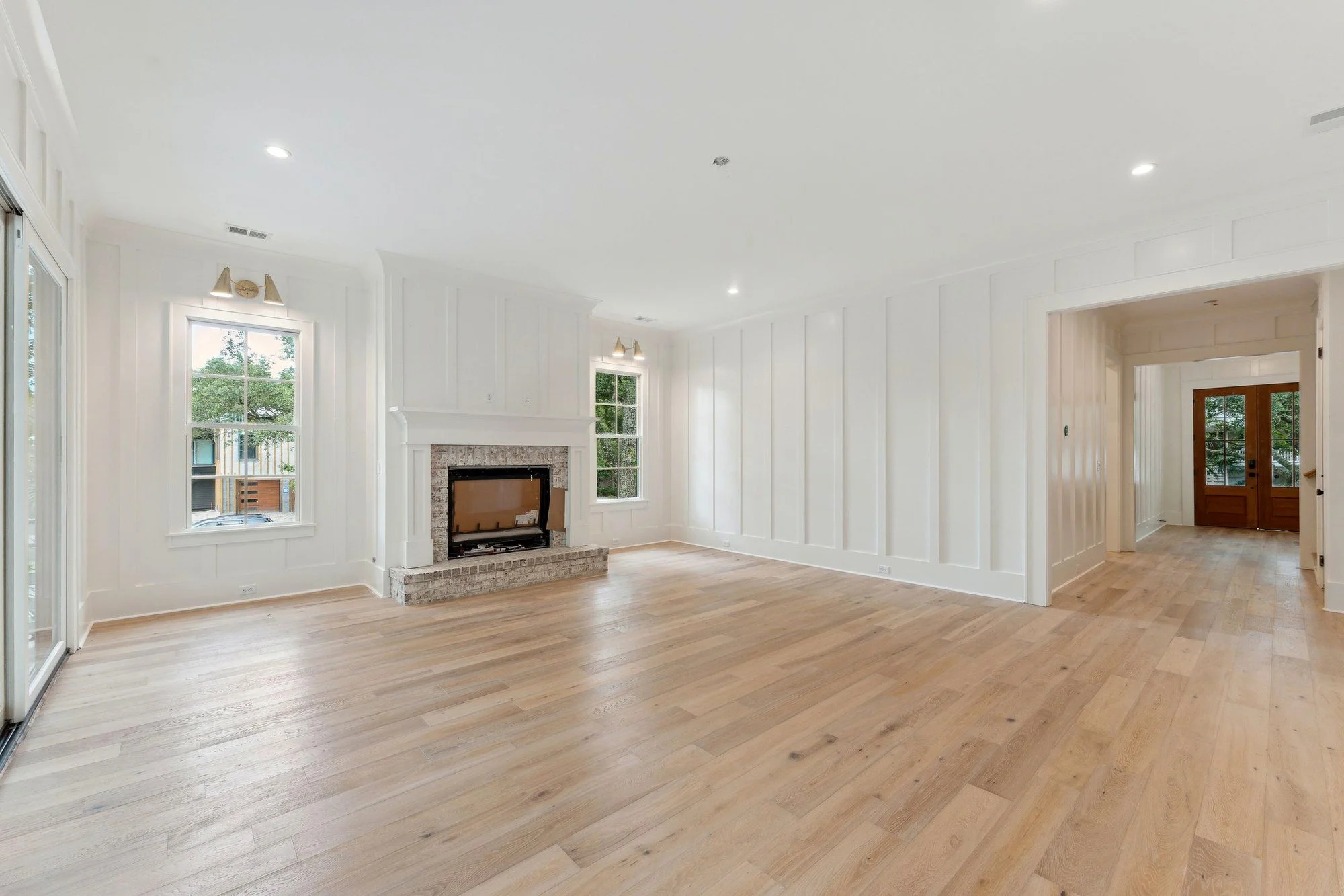 Great room with a brick-and-painted mantel fireplace, looking back to the front door.