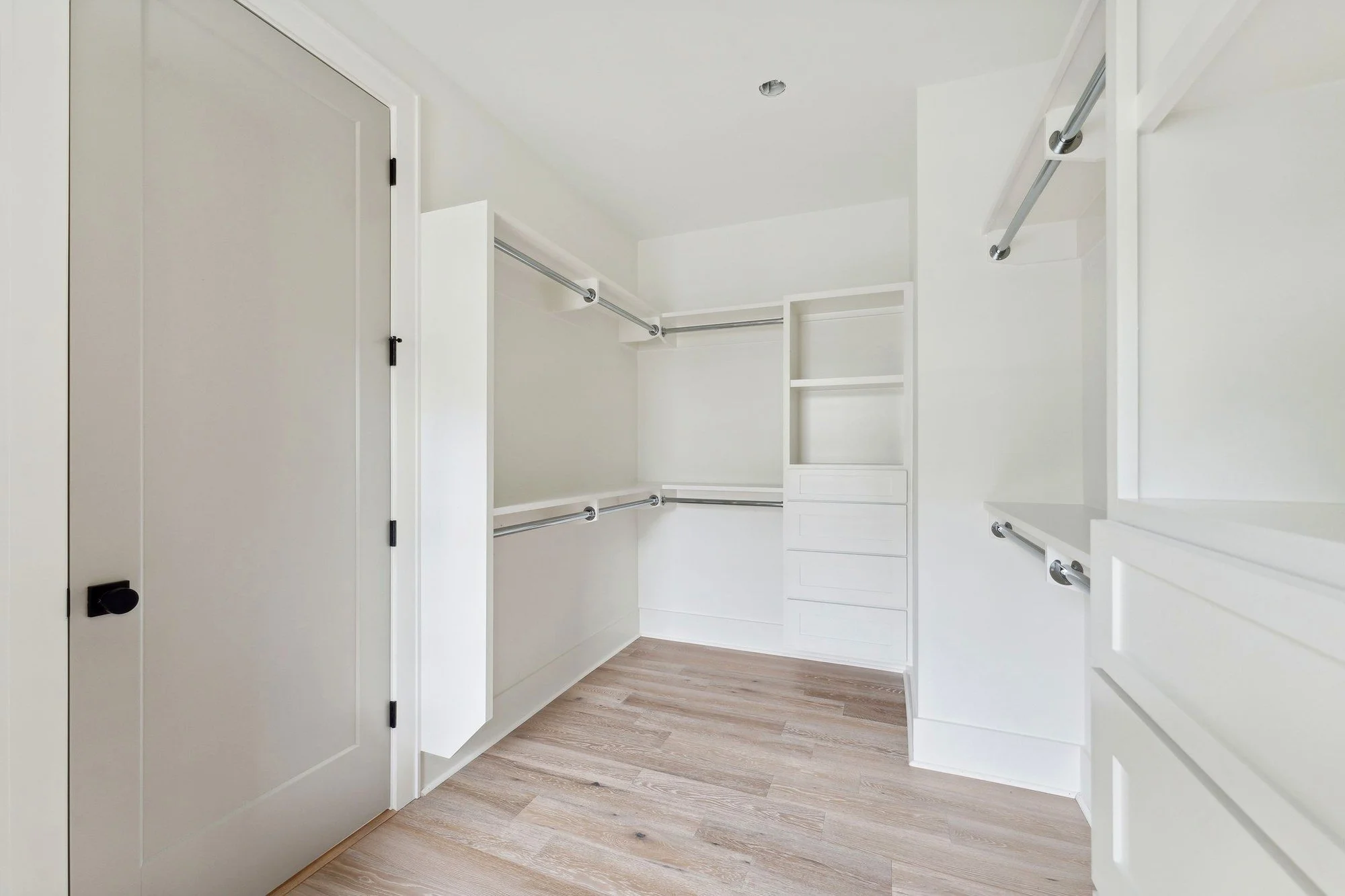 Walk-in closet with custom shelving and white oak floors.