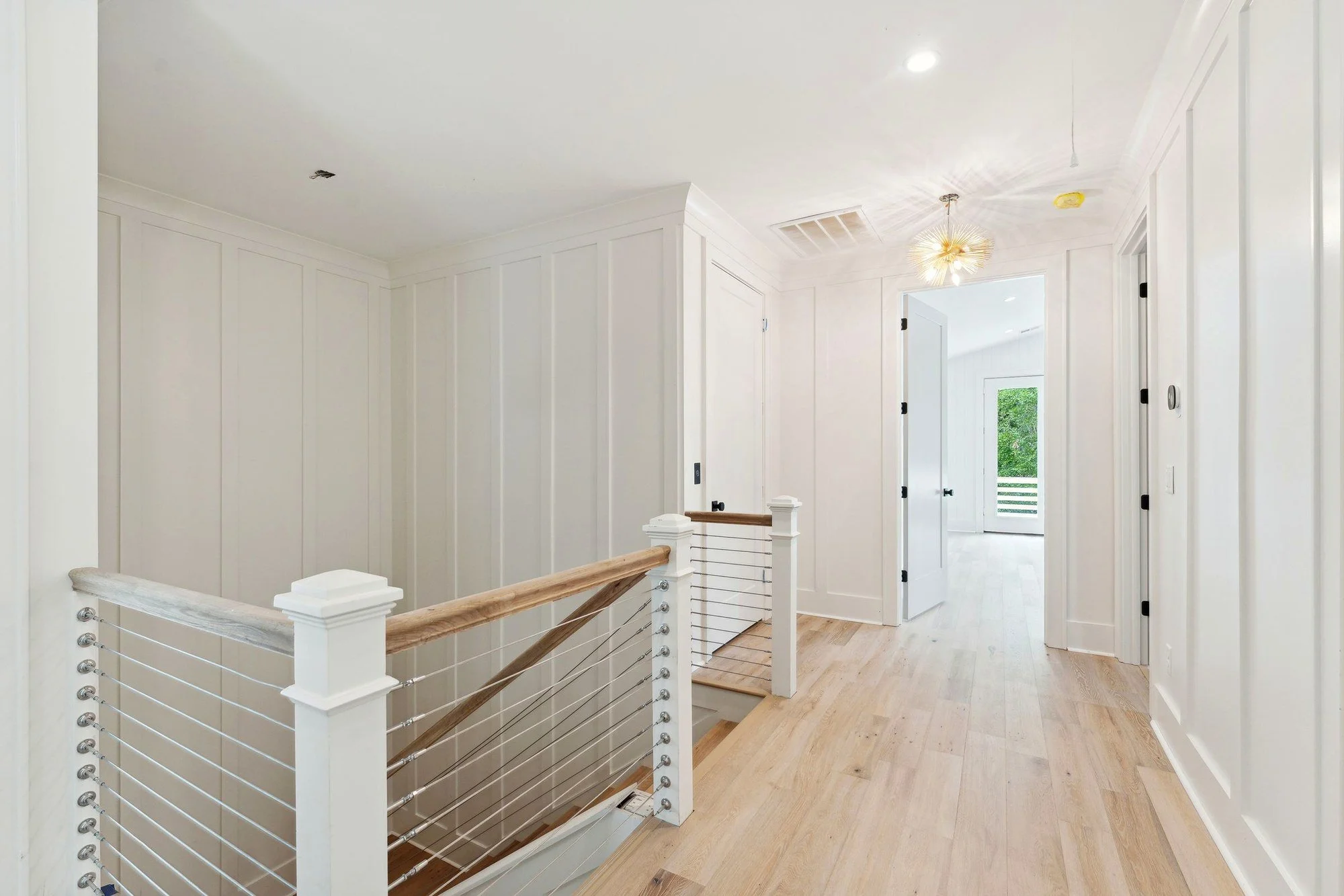 Upstairs landing with a white oak stair and cable rail.