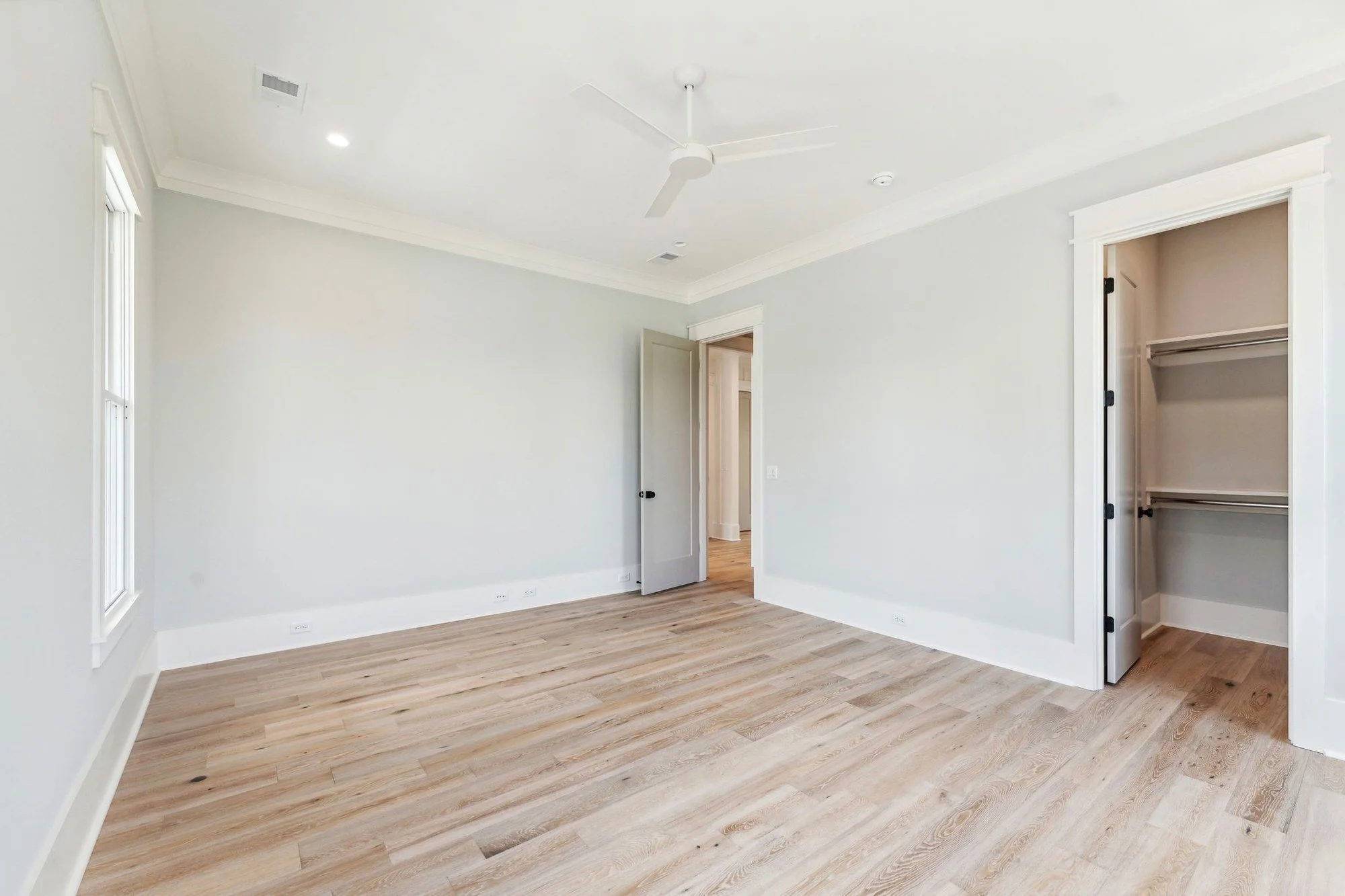 Bedroom with walk-in closet and white oak floors in a Daniel Island SC custom home