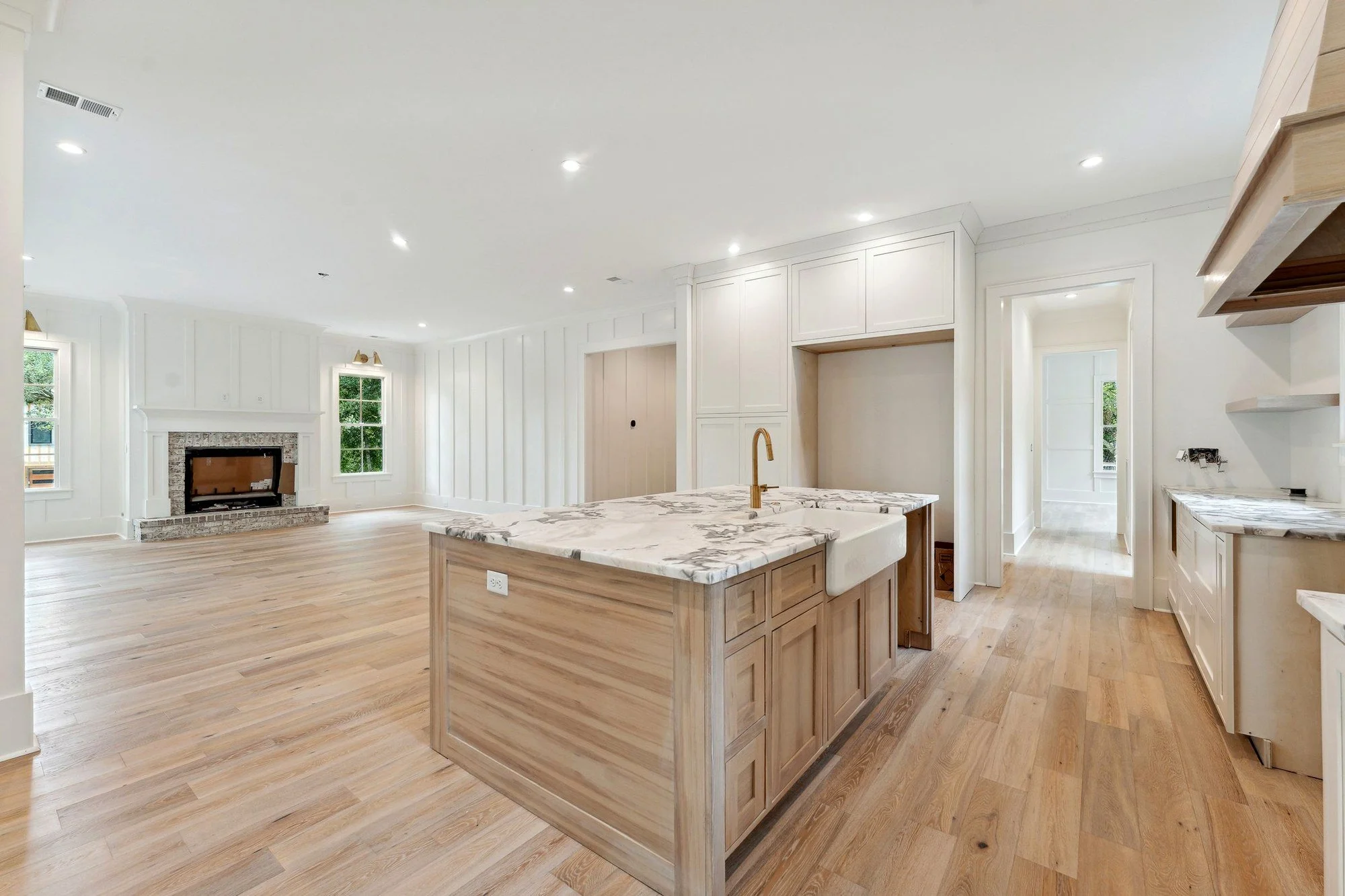 Kitchen open to the great room, with floating white oak shelves and marble counters.