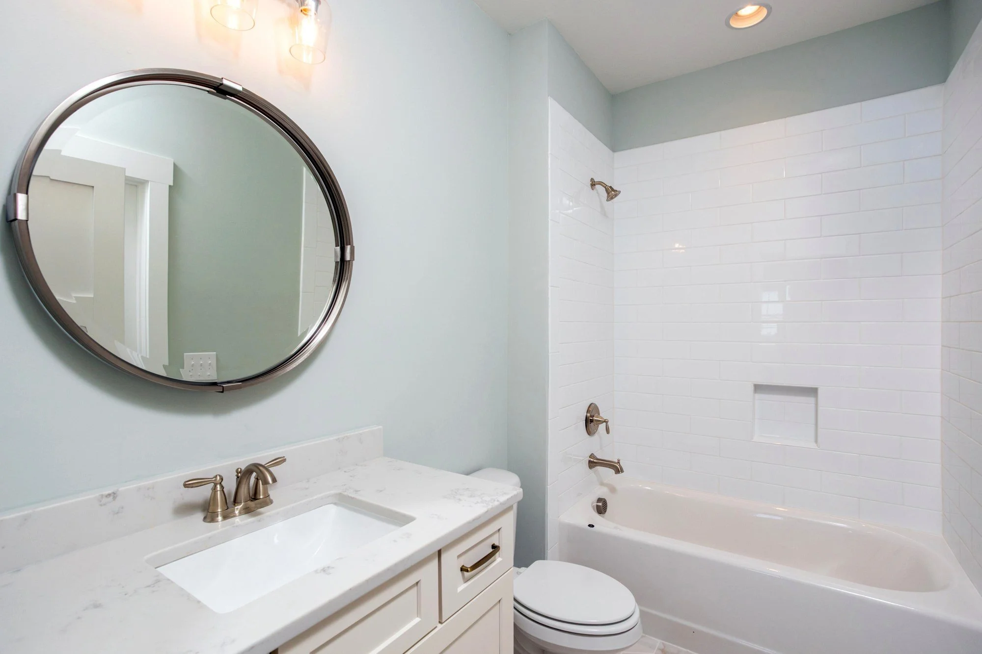 Guest bath with round mirror and custom tile in a Charleston SC custom home build