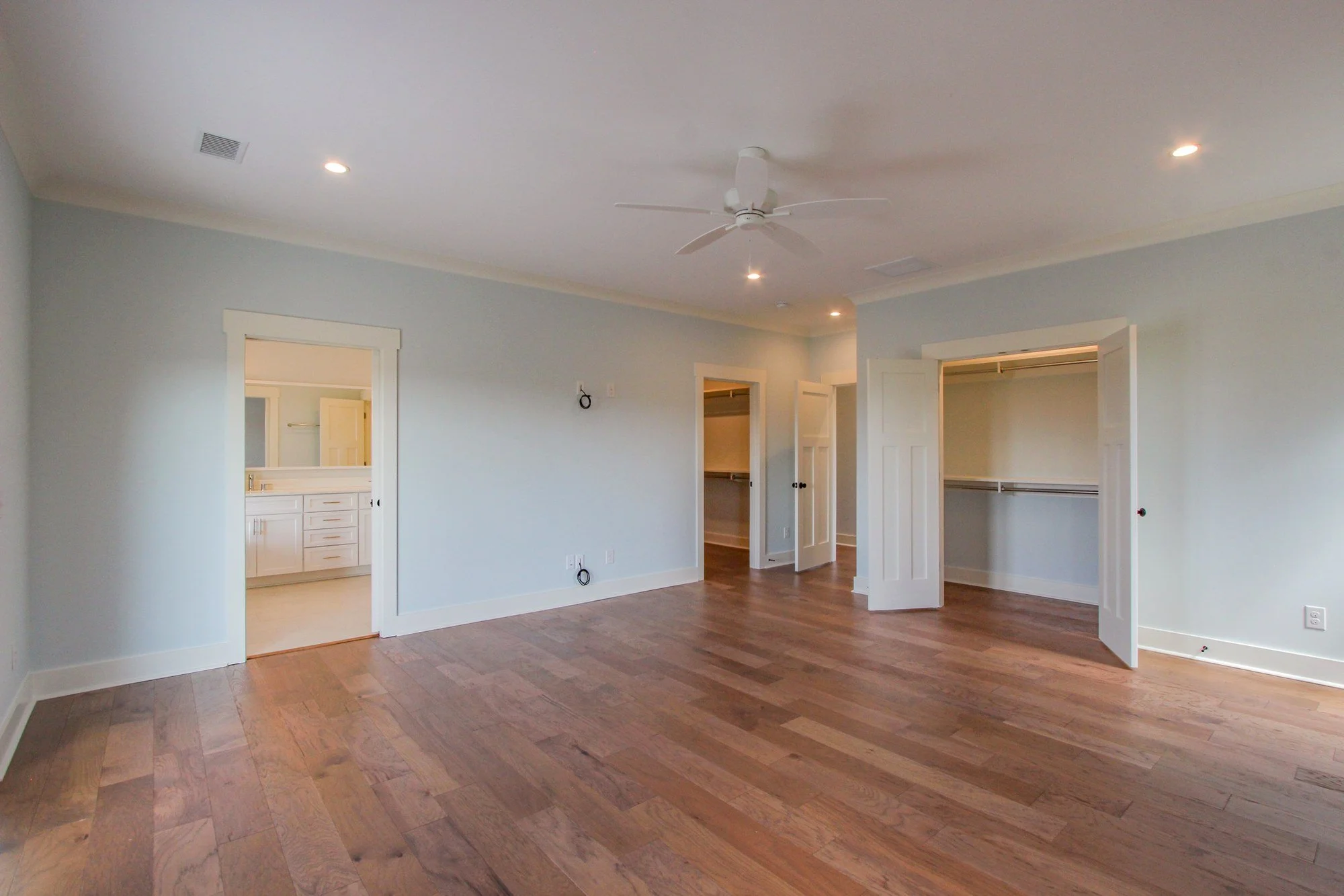 Luxury primary bedroom suite with heart pine flooring in Charleston SC