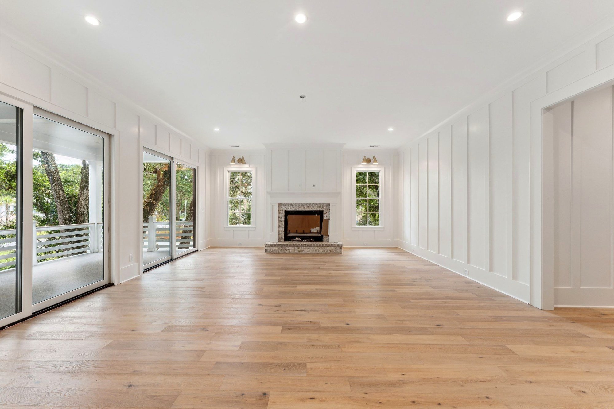 Great room with the sliders open to the covered porch and the oaks beyond.