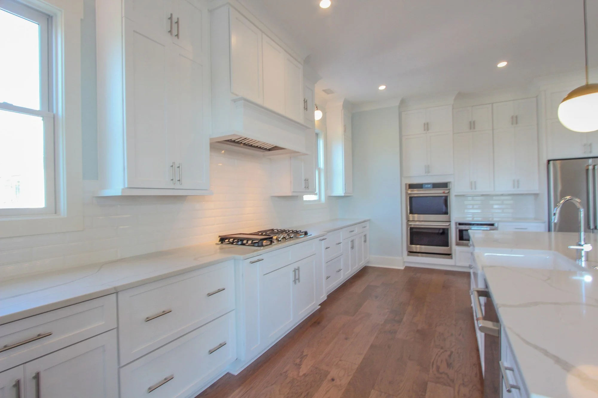 Gourmet kitchen with wall ovens and subway tile range backplate by Iconic Developments