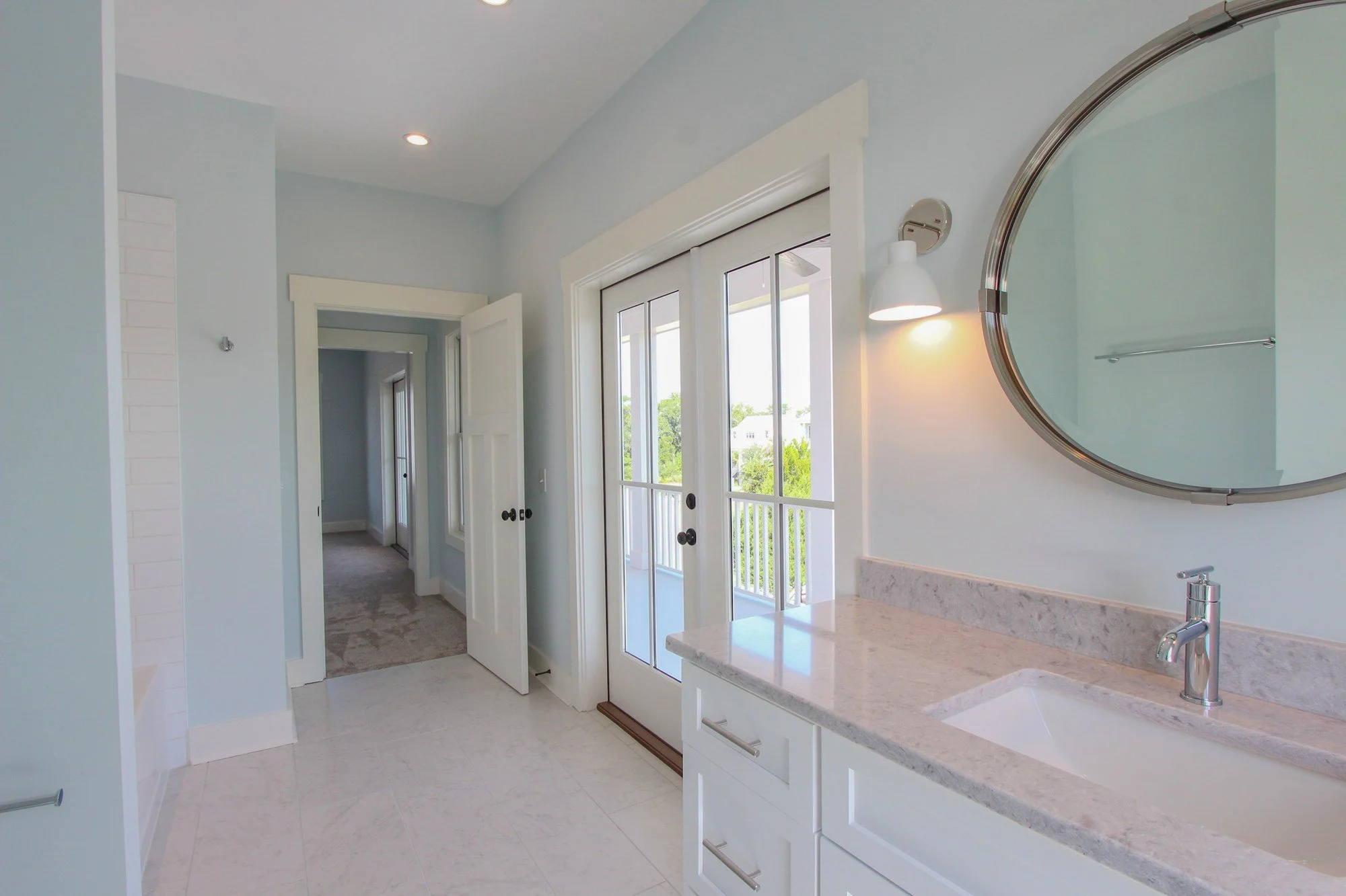 Guest bathroom with round mirror and custom vanity in a Johns Island SC home build