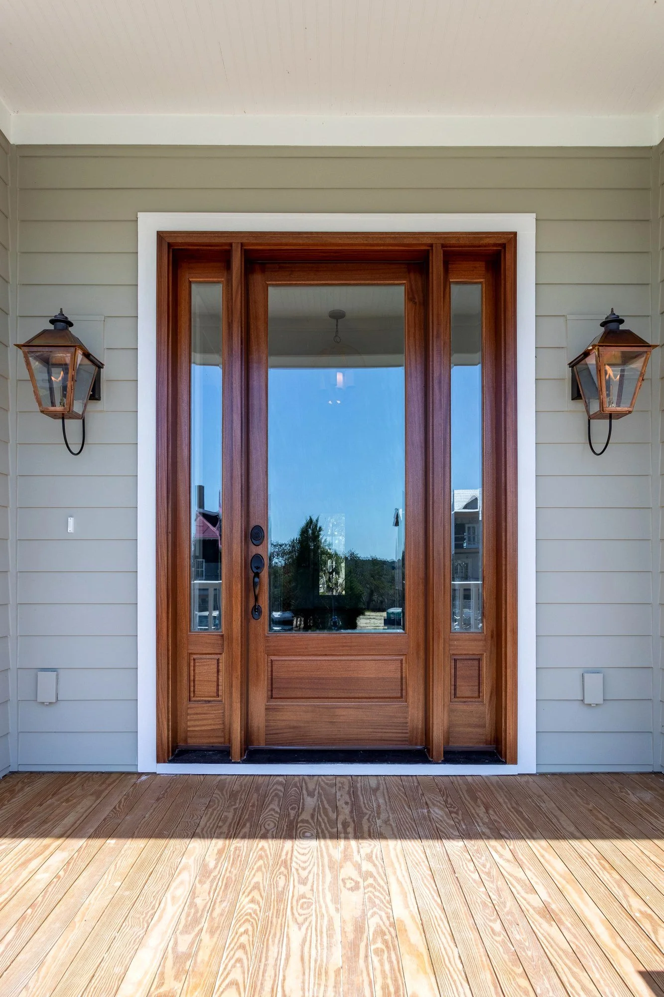 Mahogany front door flanked by copper gas lanterns on a Johns Island SC custom home