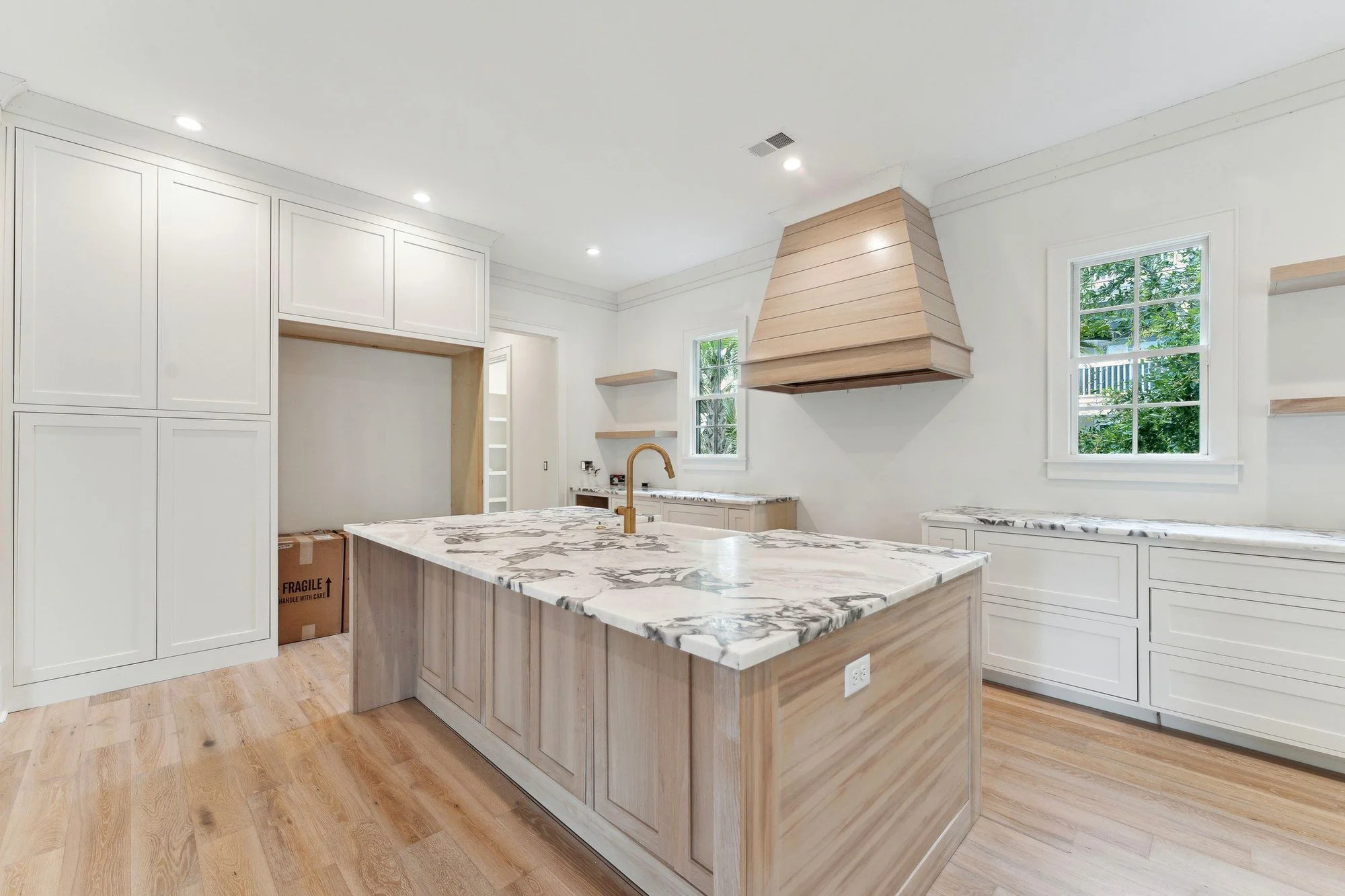 Kitchen island with book-matched marble waterfall counters and a brass faucet.