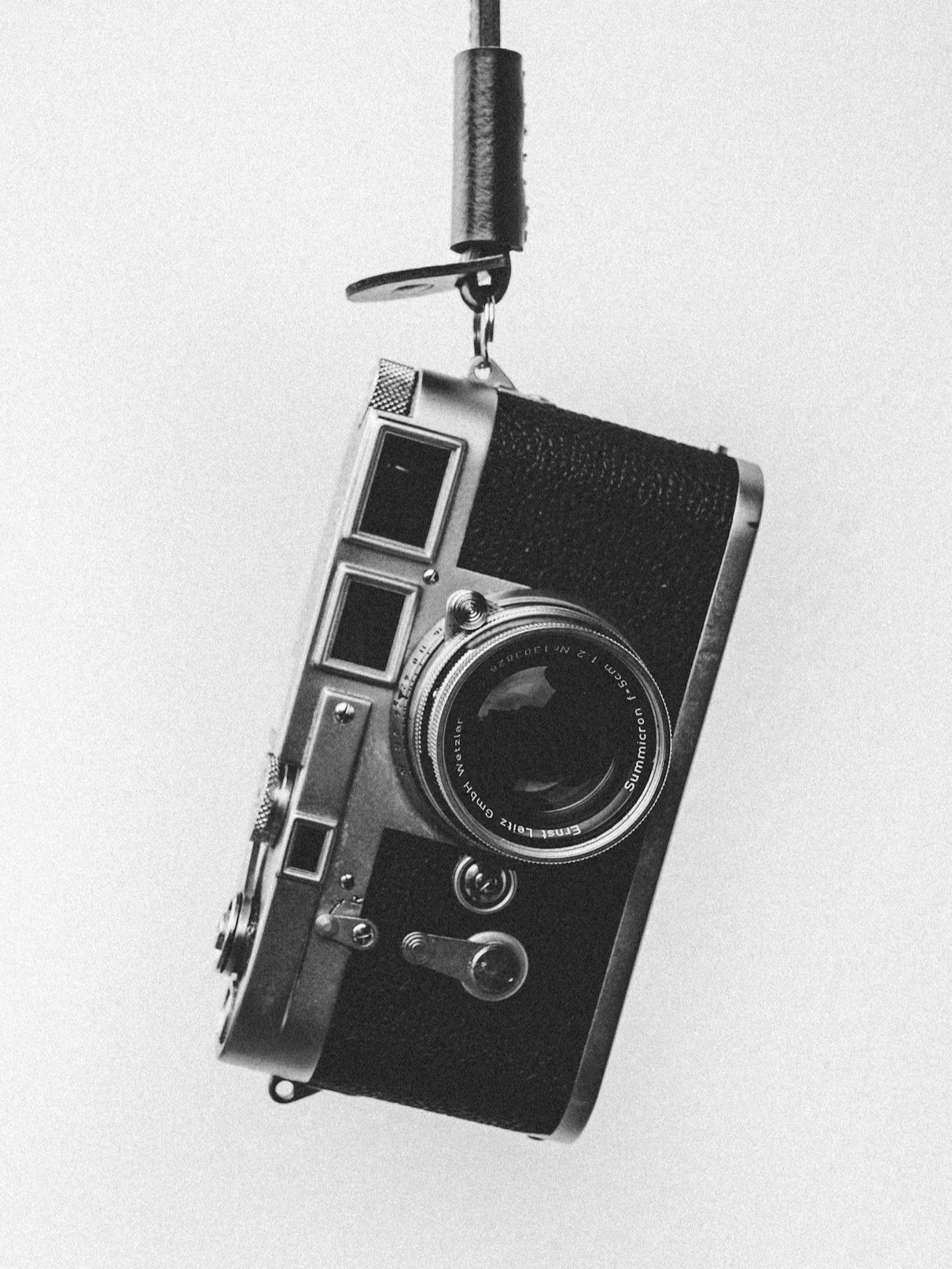 A vintage camera hanging from a ceiling hook.