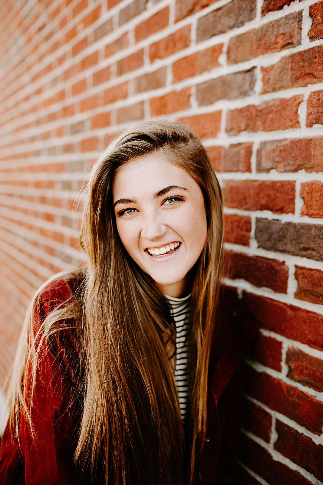 a senior photo at their senior session by a brick wall at Carmel, Indiana