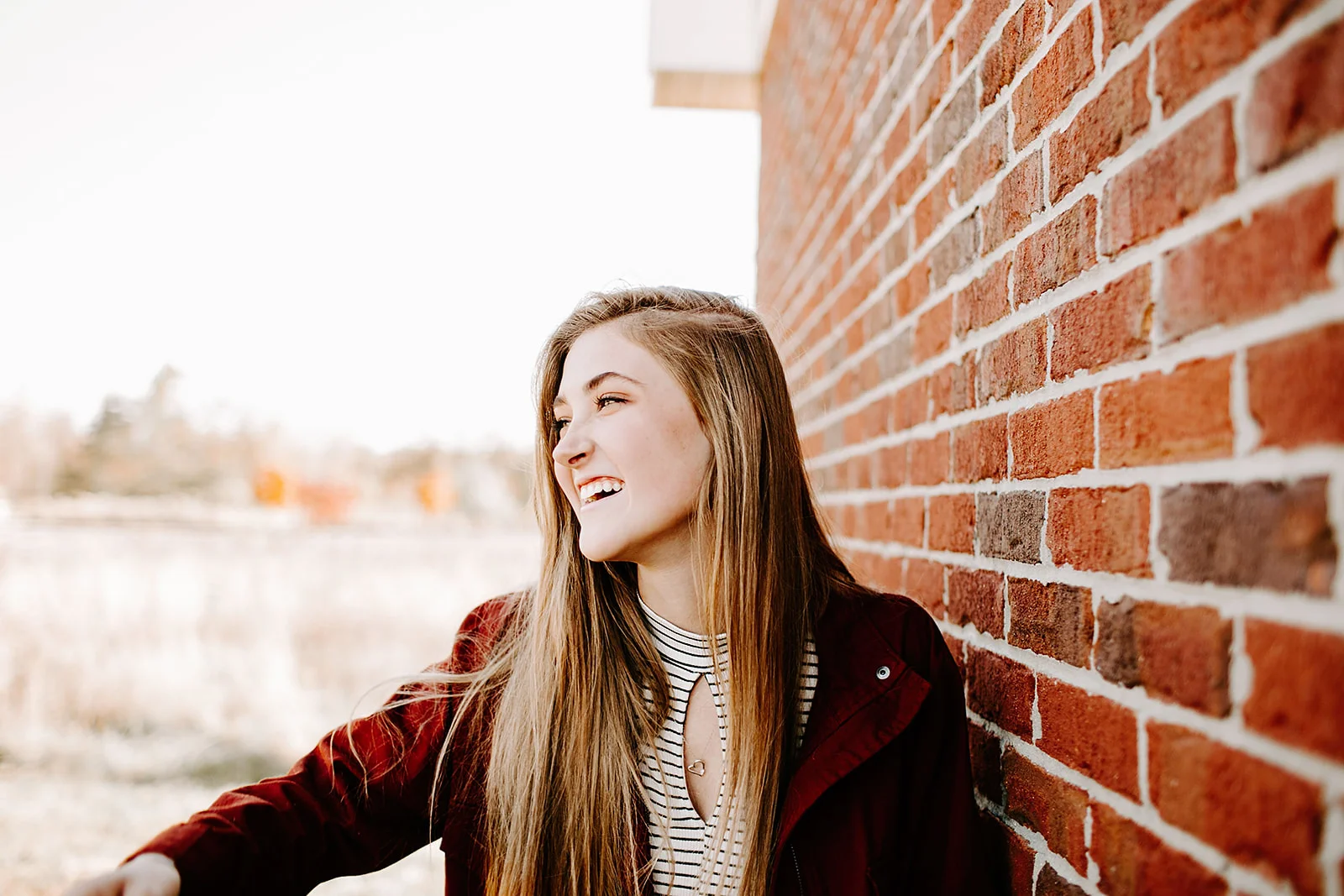 a senior photo at their senior session by a brick wall at Carmel, Indiana