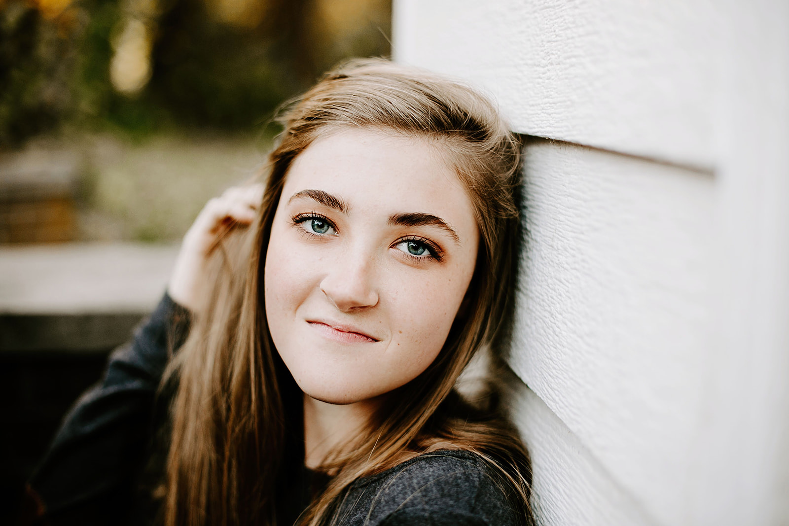 a senior photo at their senior session by a white wall at Carmel, Indiana