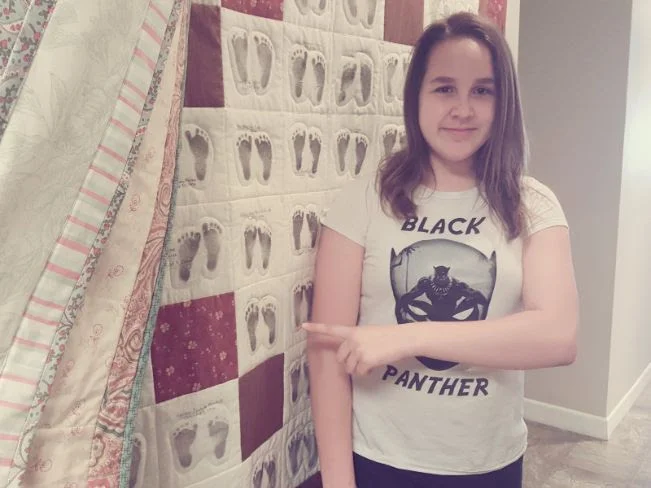 One of our 'babies' now nearly a teen - checking out her tiny footprints, on one of the first quilts!