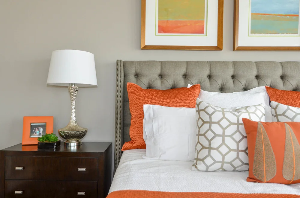 Modern grey tufted headboard with art above and orange accents