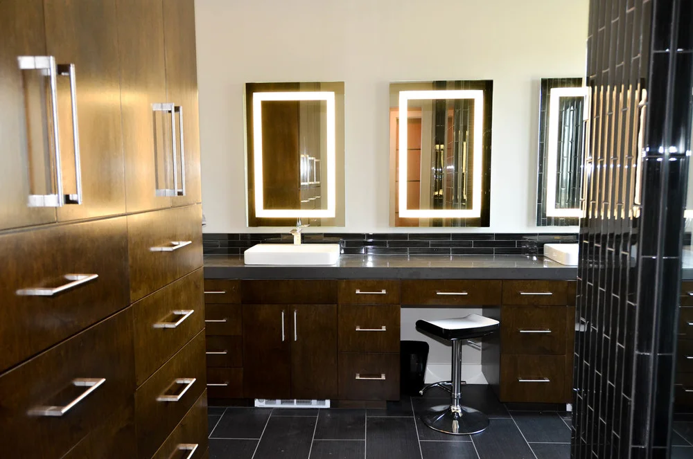 Modern master bathroom with dark wood and self-lit vanity mirrors