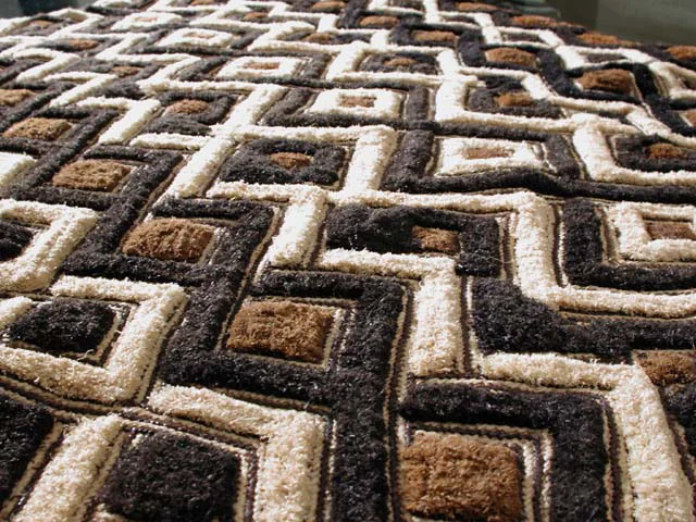 It’s primitive nature allows Kuba Cloth to be simultaneously ancient and ritualistic, in it’s creation. Graphically, the textile is distinctive and evocative of the Congo. The earth and terrain of it’s origin is seen directly within the rich strands of the textile’s weave. Kuba cloth is handwoven using strands from raffia palm leaves. The raffia palm tree is known for having the longest leaves in the world. The raffia strands are dyed in a variety of earth tones, using vegetable dyes. Textile variations are executed on rectangular pieces of woven palm leaf fiber.